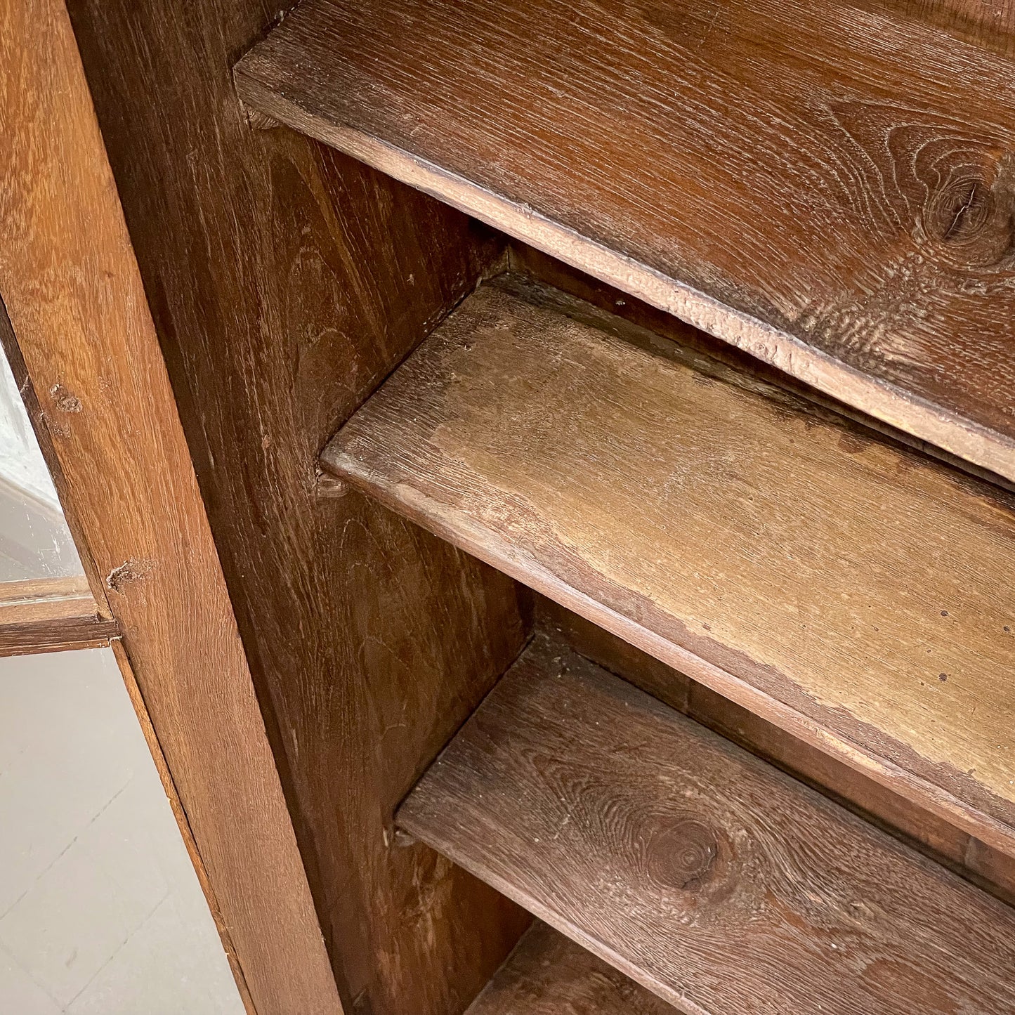 Wooden bookshelf with three shelves on a white floor.