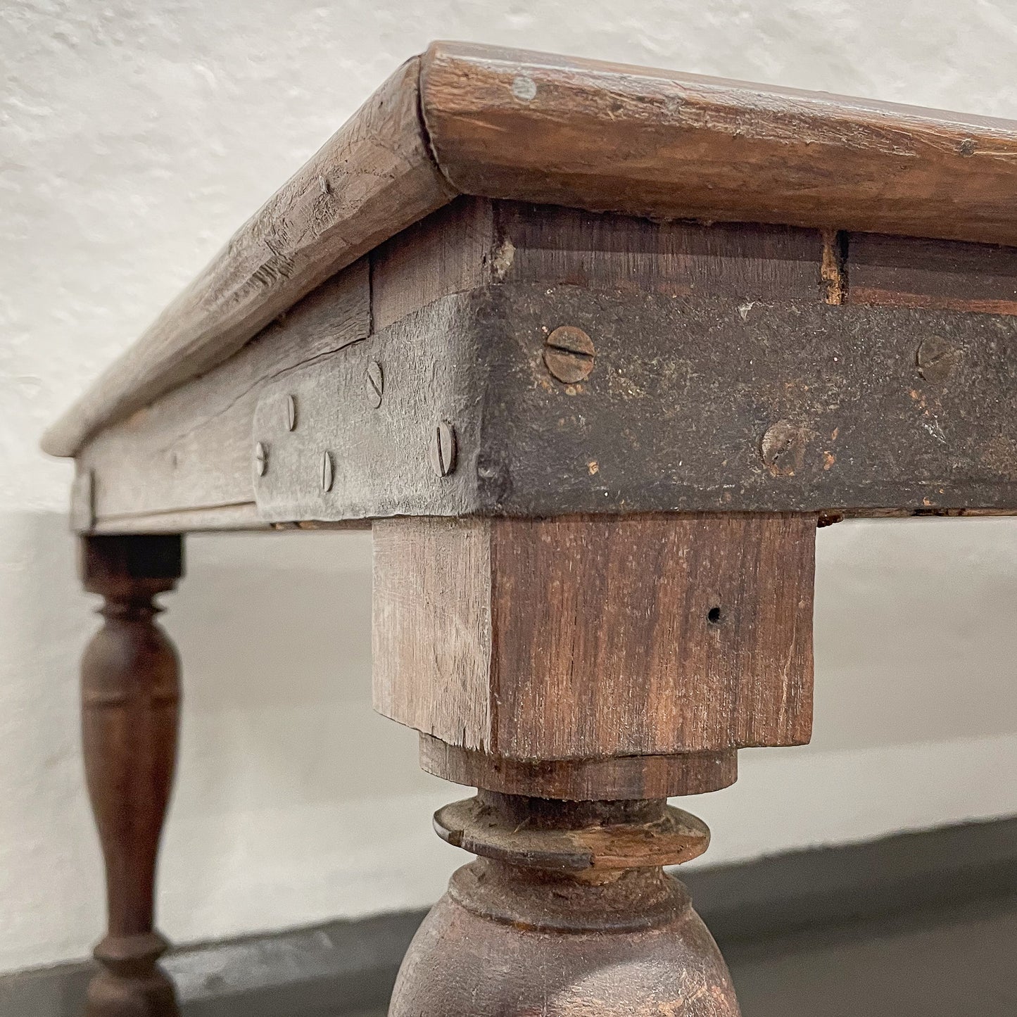 Close-up of an old wooden table with a visible joint and leg.