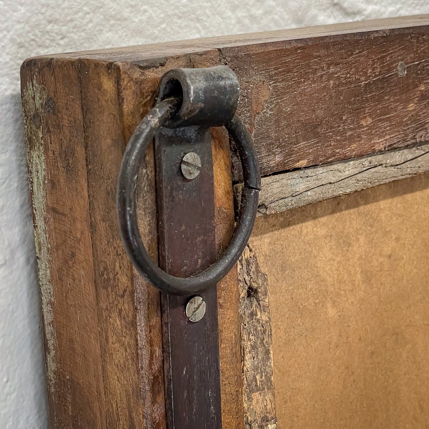 Close-up of a rustic wooden door with a metal handle on a textured wall.