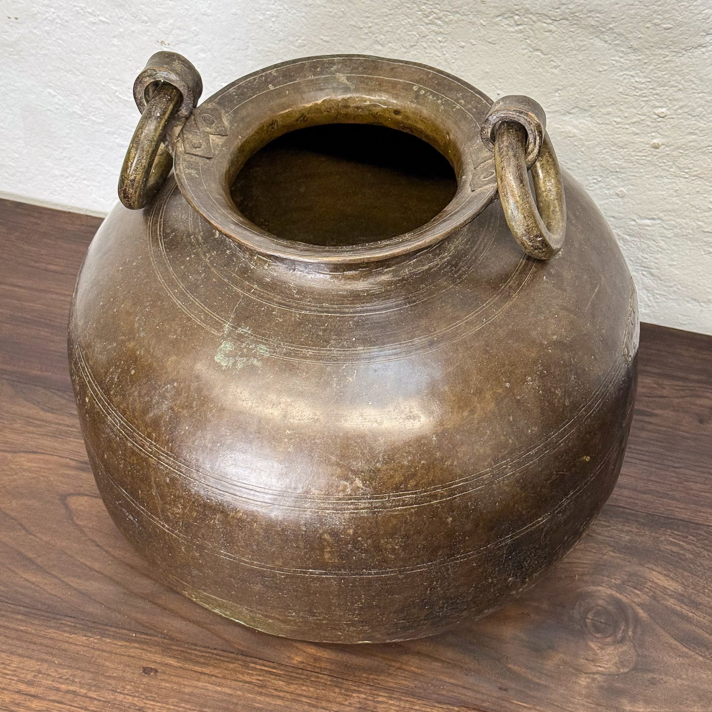 Bronze pot with ring handles on a wooden surface