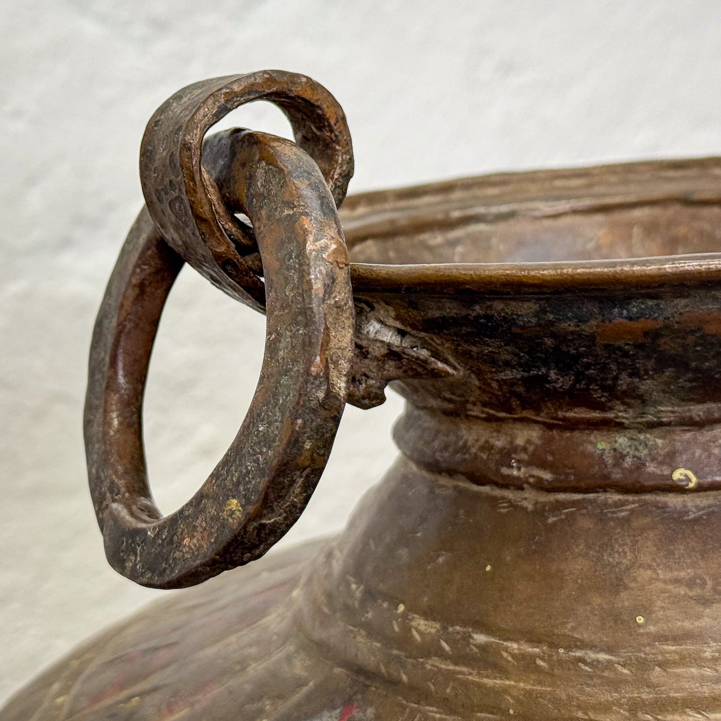 Close-up of a bronze pot with a handle on a light gray background