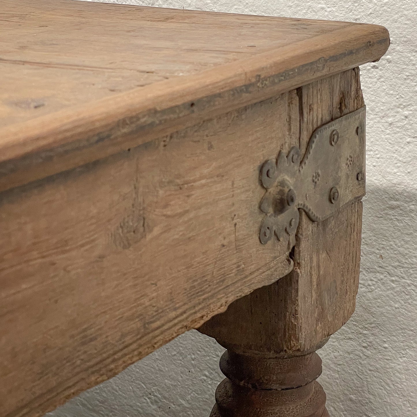 Wooden table with metal bracket against a plain wall