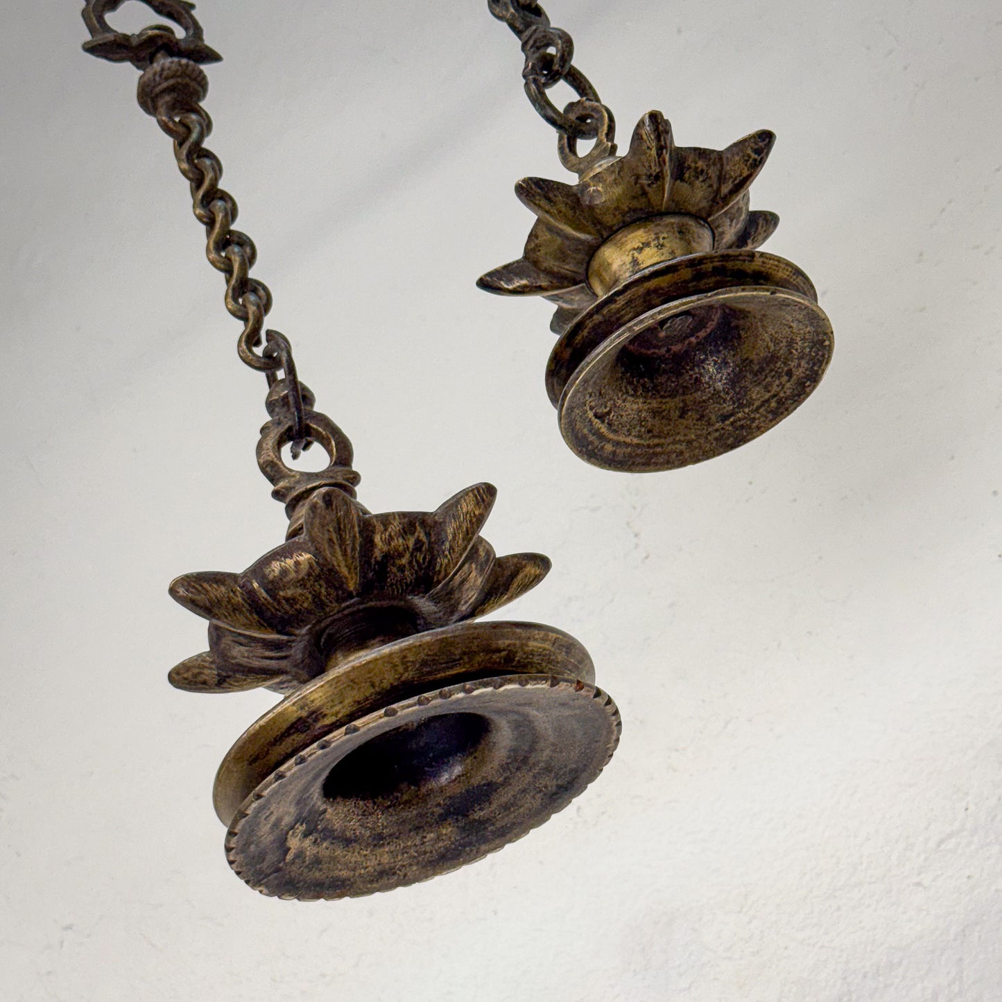 Pair of vintage bronze bells on a chain against a white background