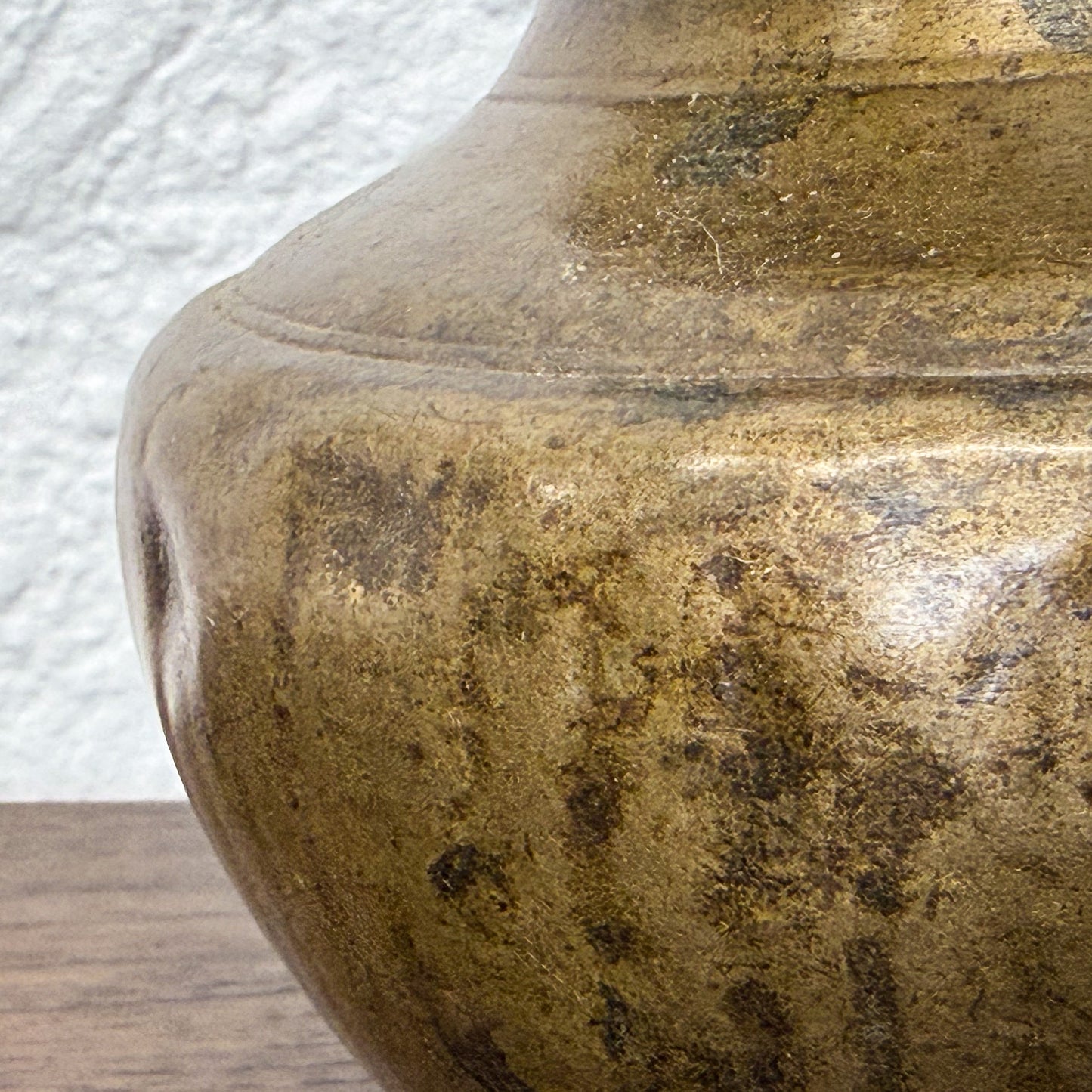 Close-up of a brown ceramic vase with textured surface on a wooden surface.