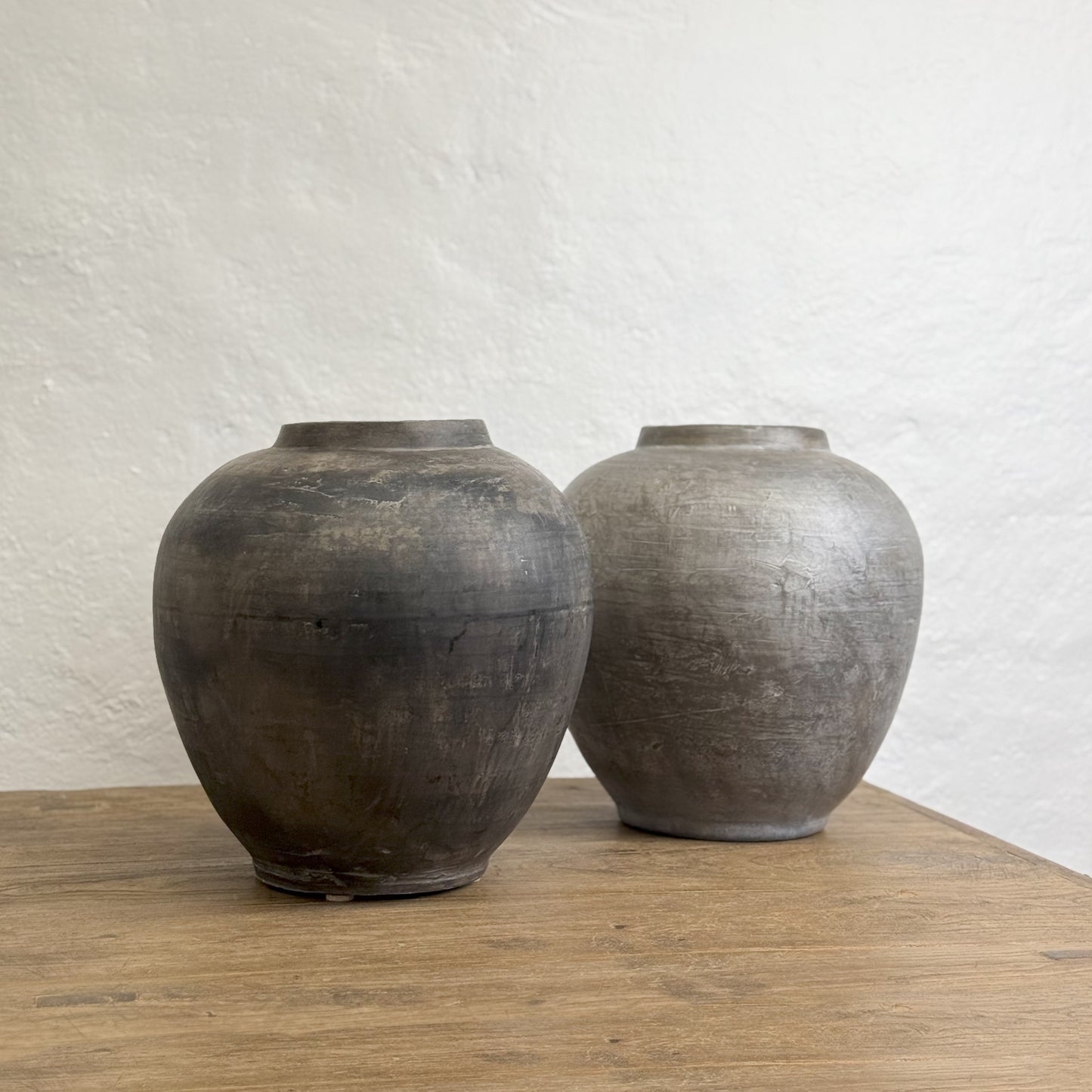A large tapered earthenware vase with a dark finish, standing against a white background.