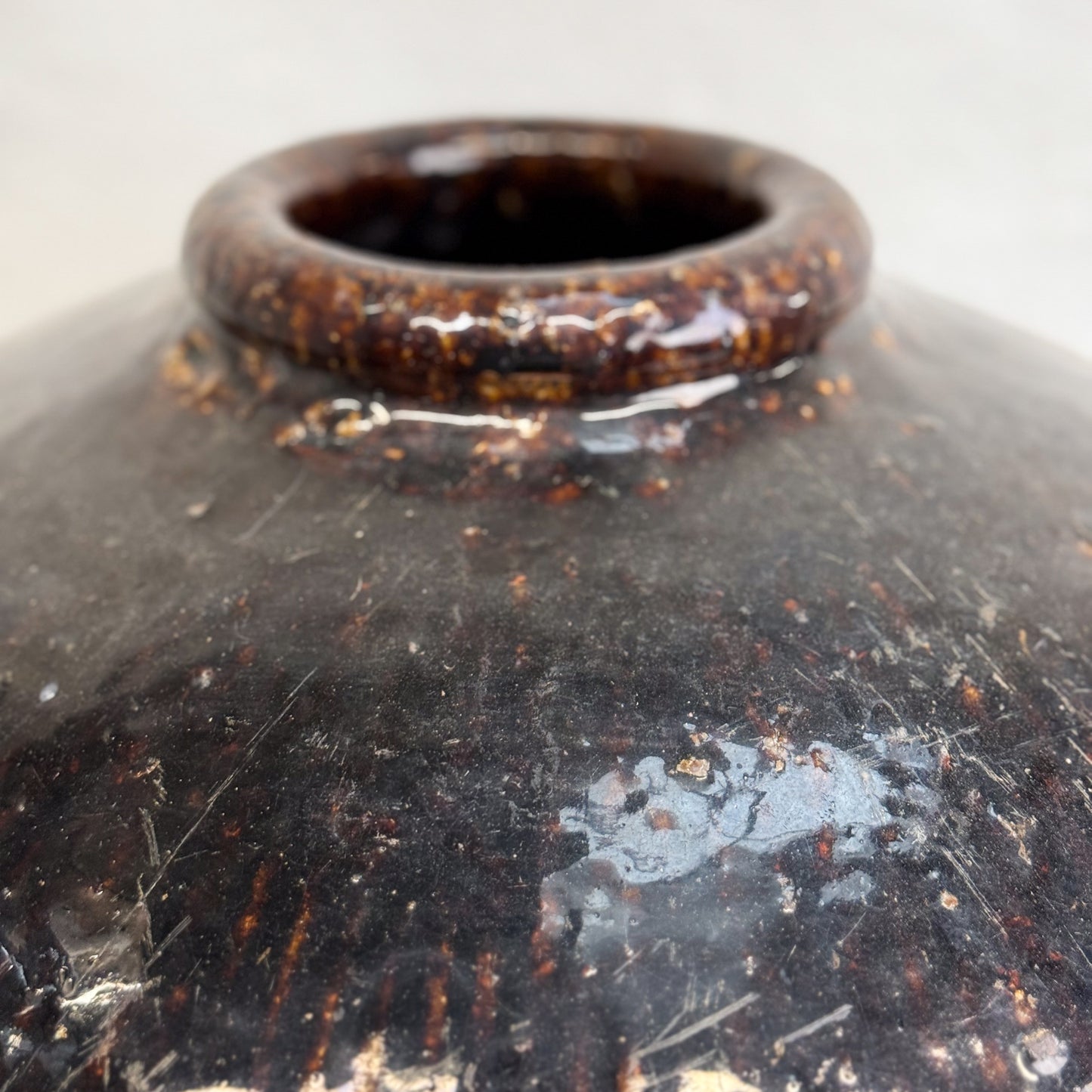 A brown ceramic rice wine pot with a textured surface, placed on a wooden surface against a white background.