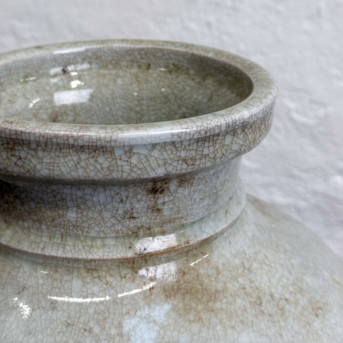A beige ceramic vase with a crackled finish and two handles, displayed against a neutral background.
