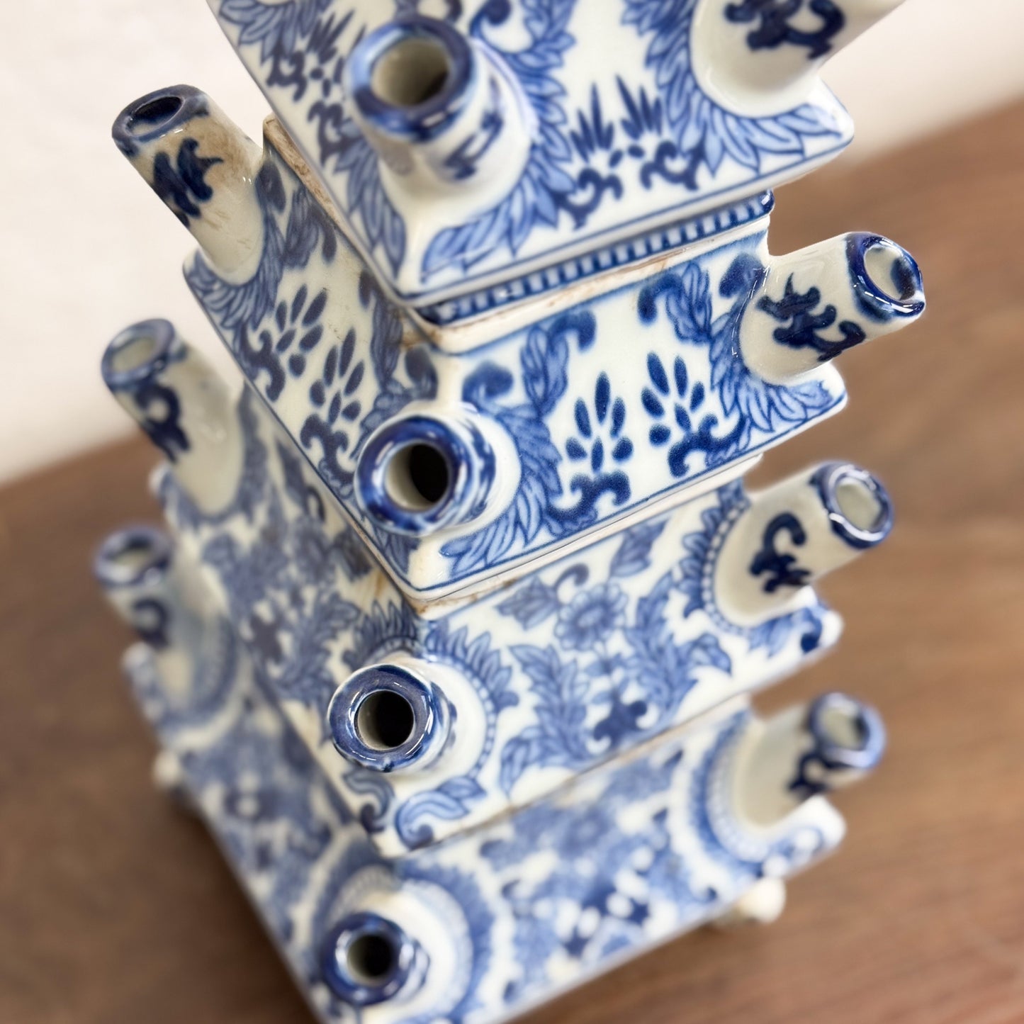 A hand-painted porcelain pagoda tulip vase with a tiered silhouette and intricate blue and white floral motifs, displayed against a neutral background.