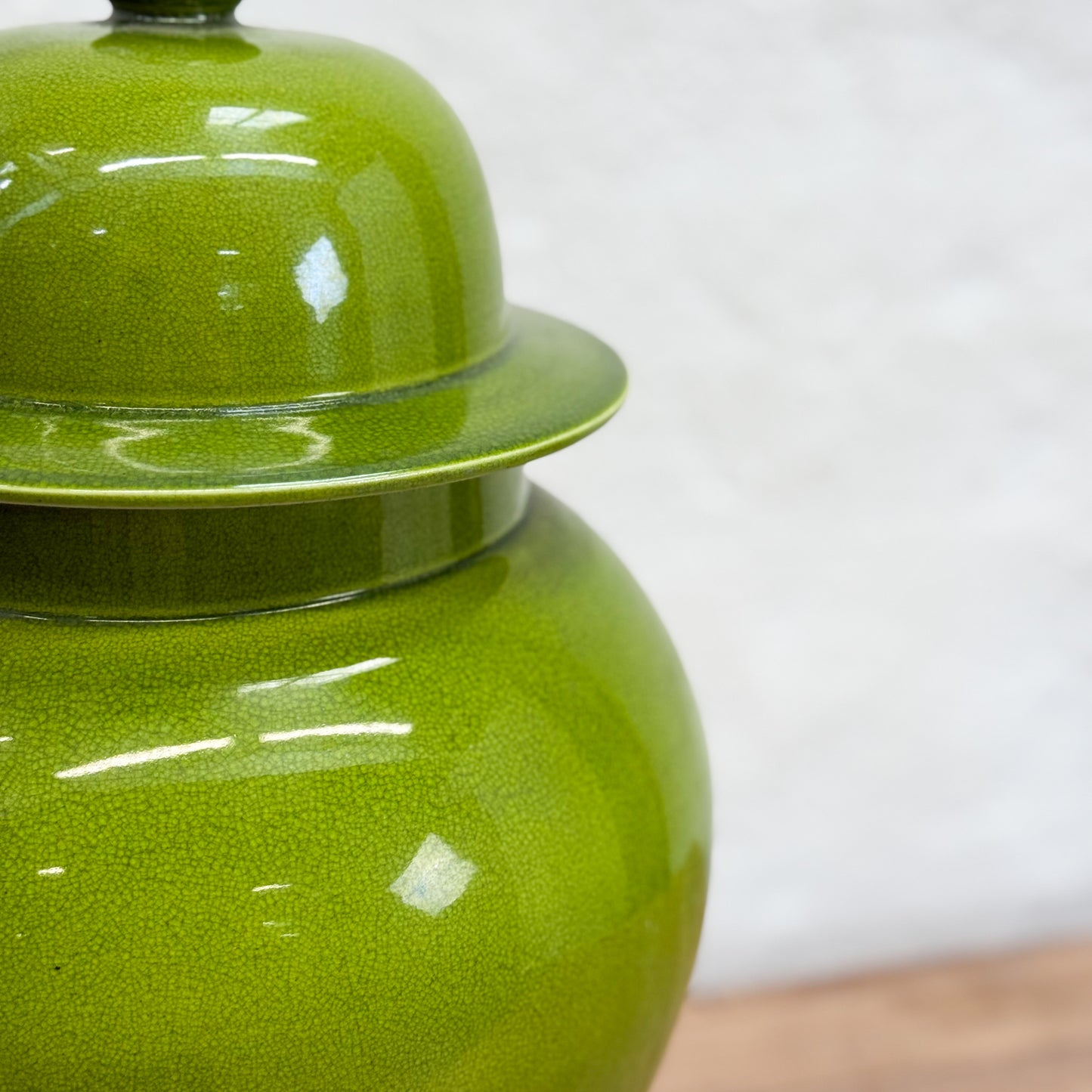 Green ceramic jar with a lid on a white background
