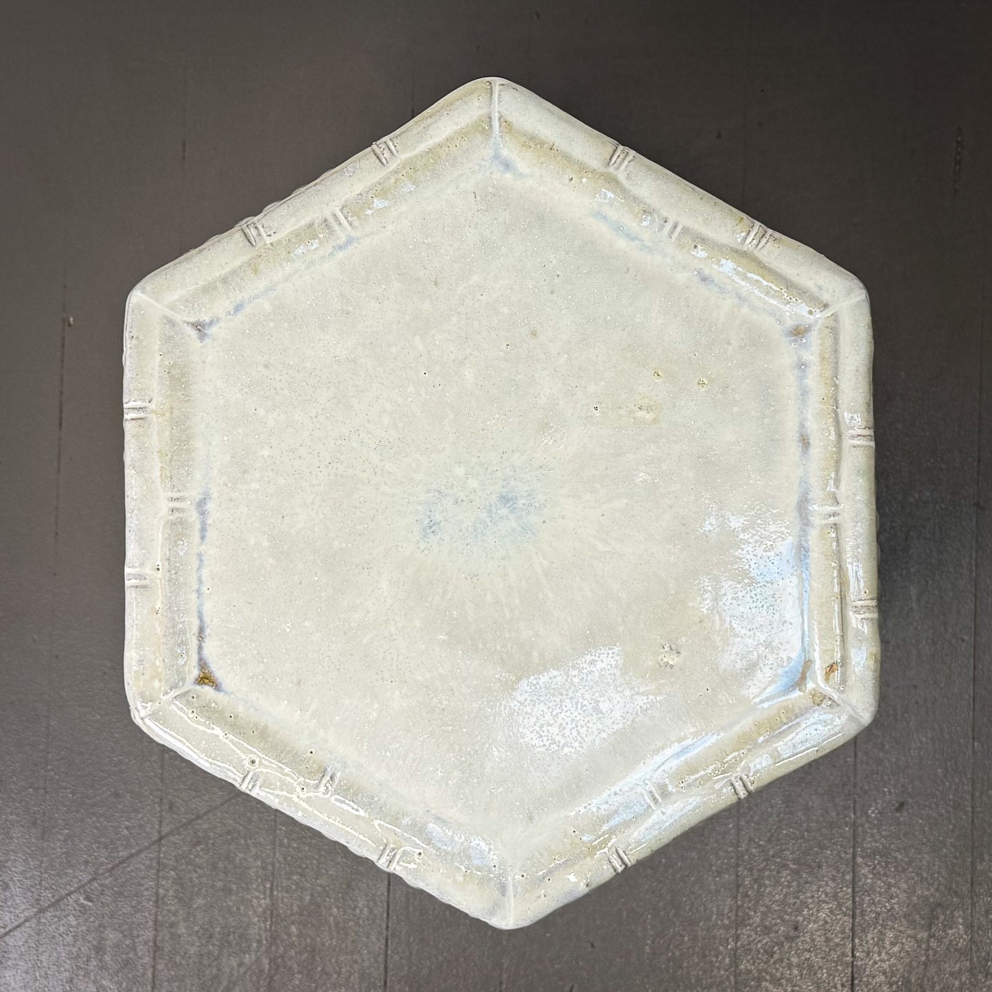 Hexagonal ceramic plate with a textured surface on a gray background