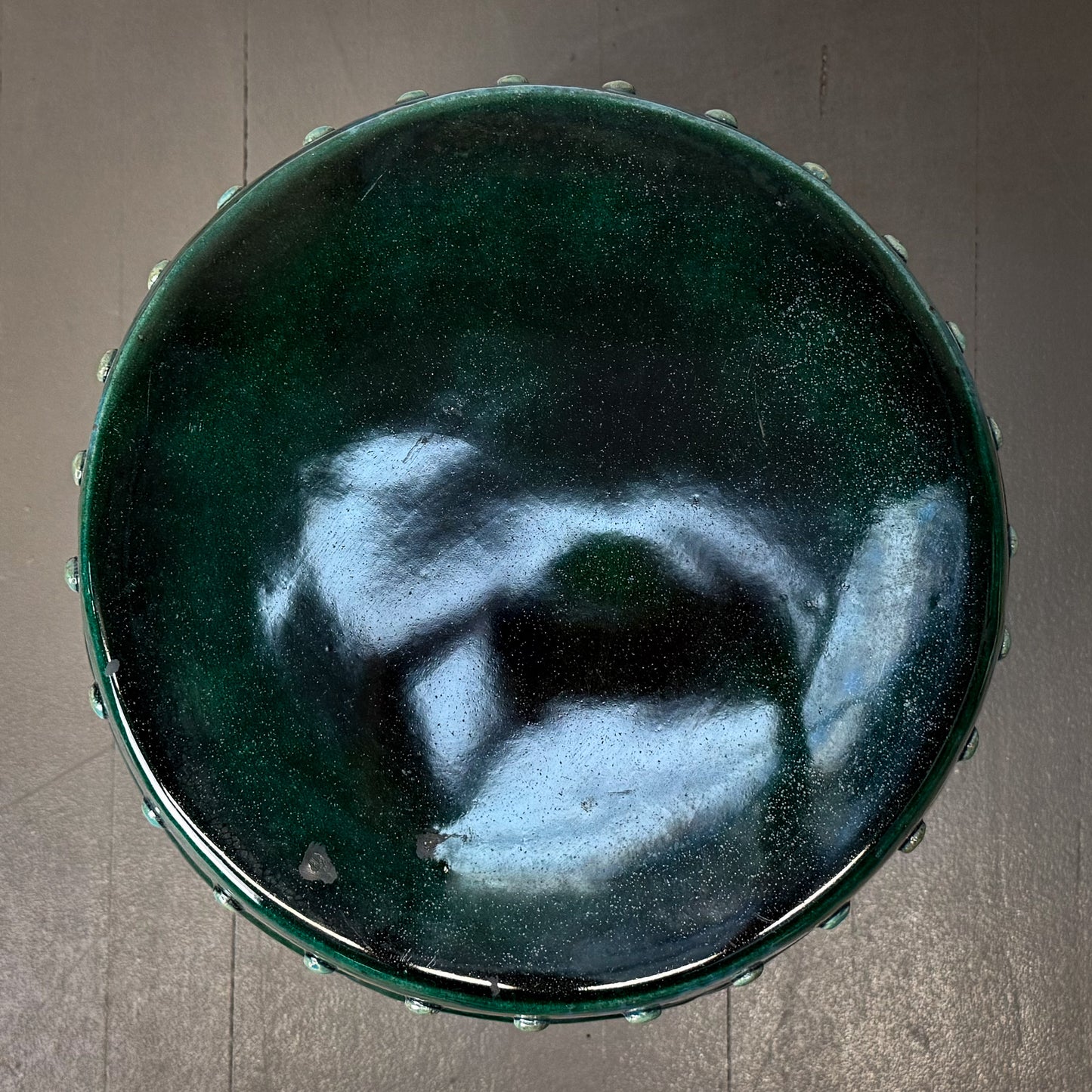 Green ceramic bowl with a textured surface on a gray background
