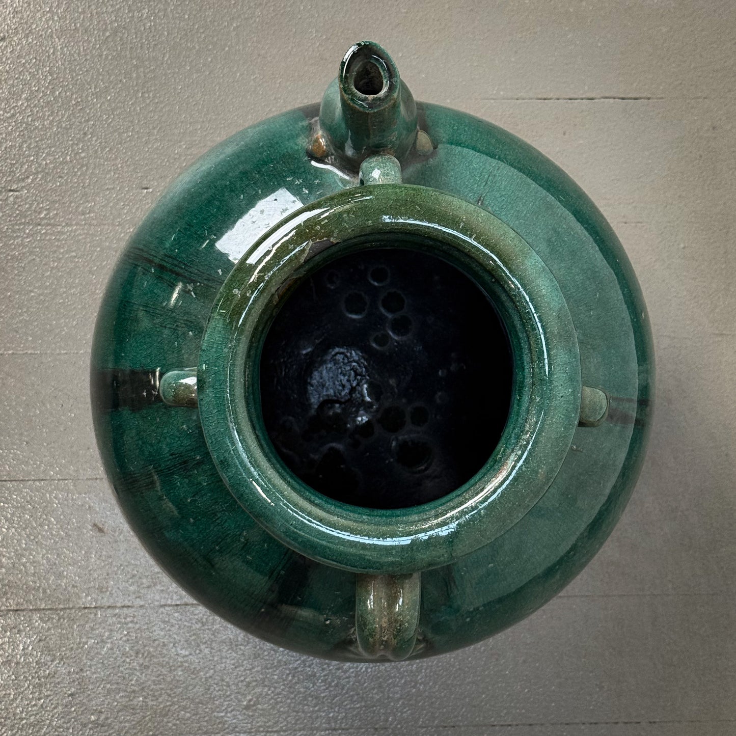 Green ceramic object with a textured interior on a gray surface