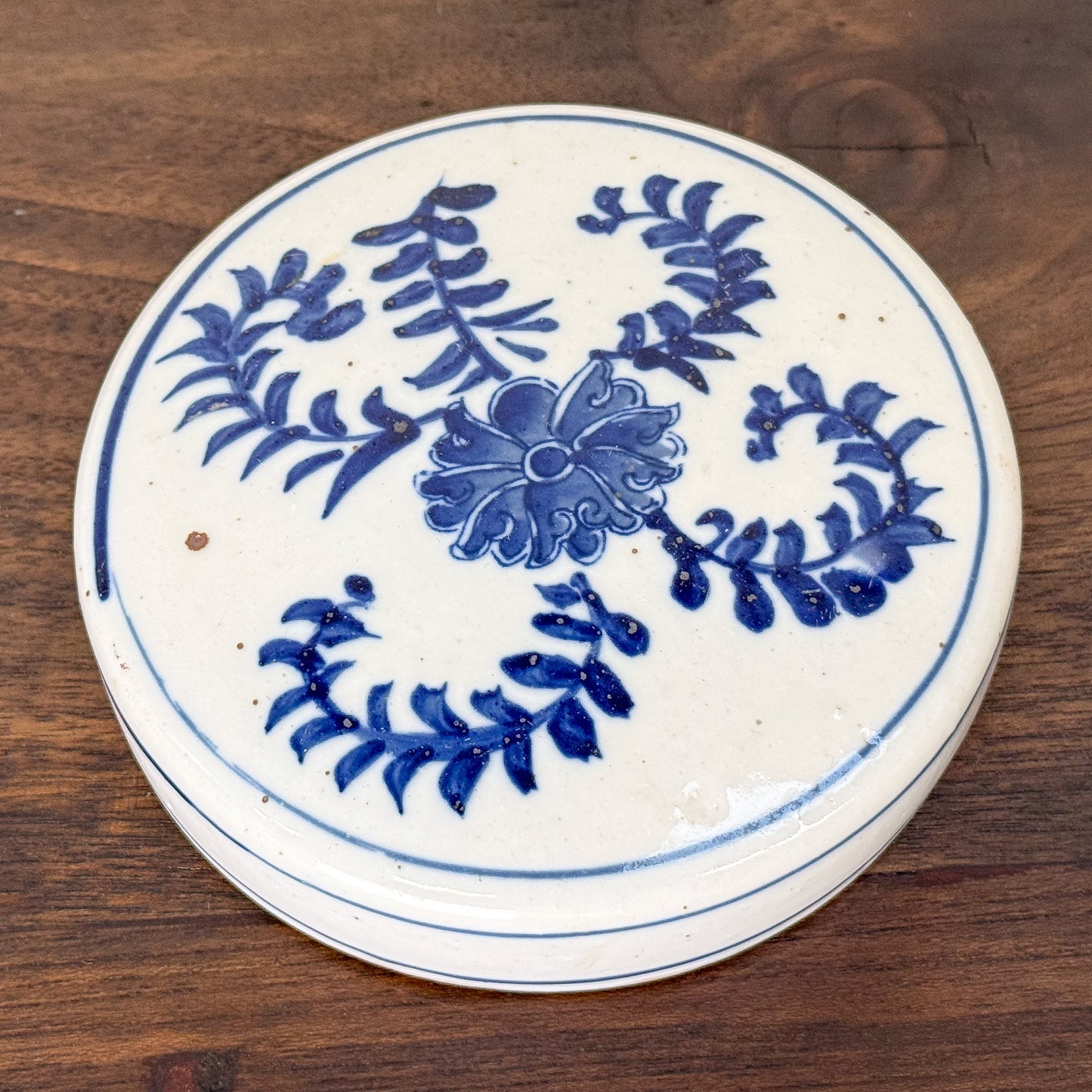 Ceramic coaster with blue floral design on a wooden surface
