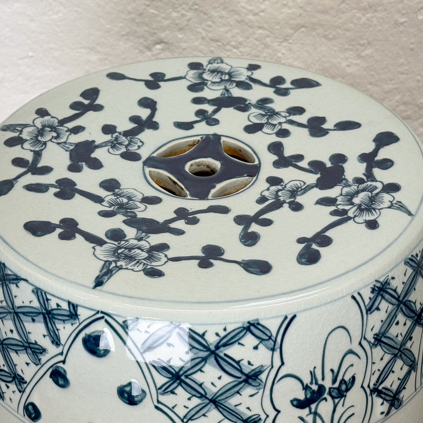 Round ceramic stool with blue floral patterns on a textured surface