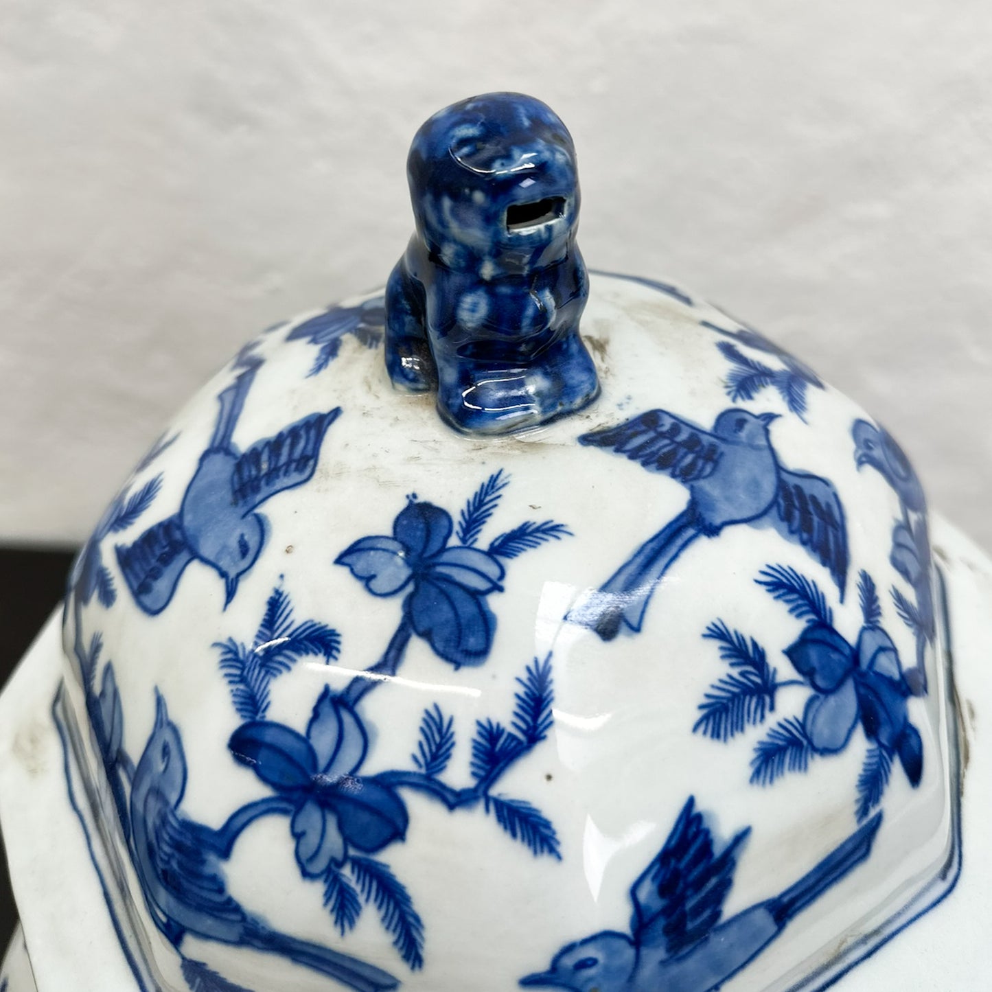 A blue and white hexagonal porcelain jar with birds and vine pattern, displayed against a neutral background.