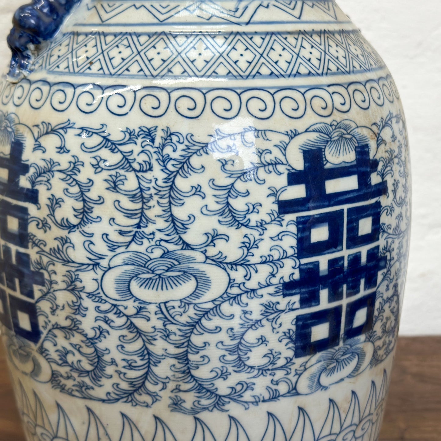 A large blue and white porcelain vase with floral patterns and Chinese characters painted on it.
