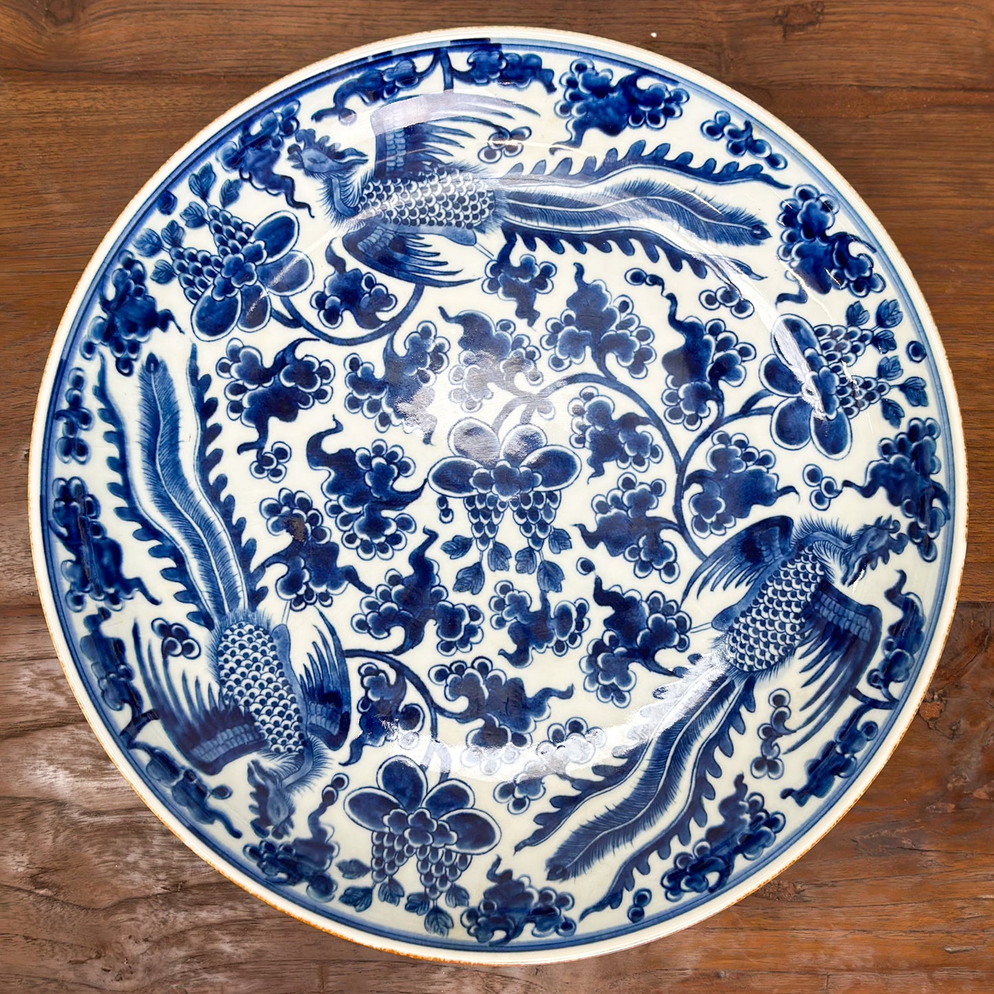A large, blue and gold porcelain plate with a floral and phoenix pattern.