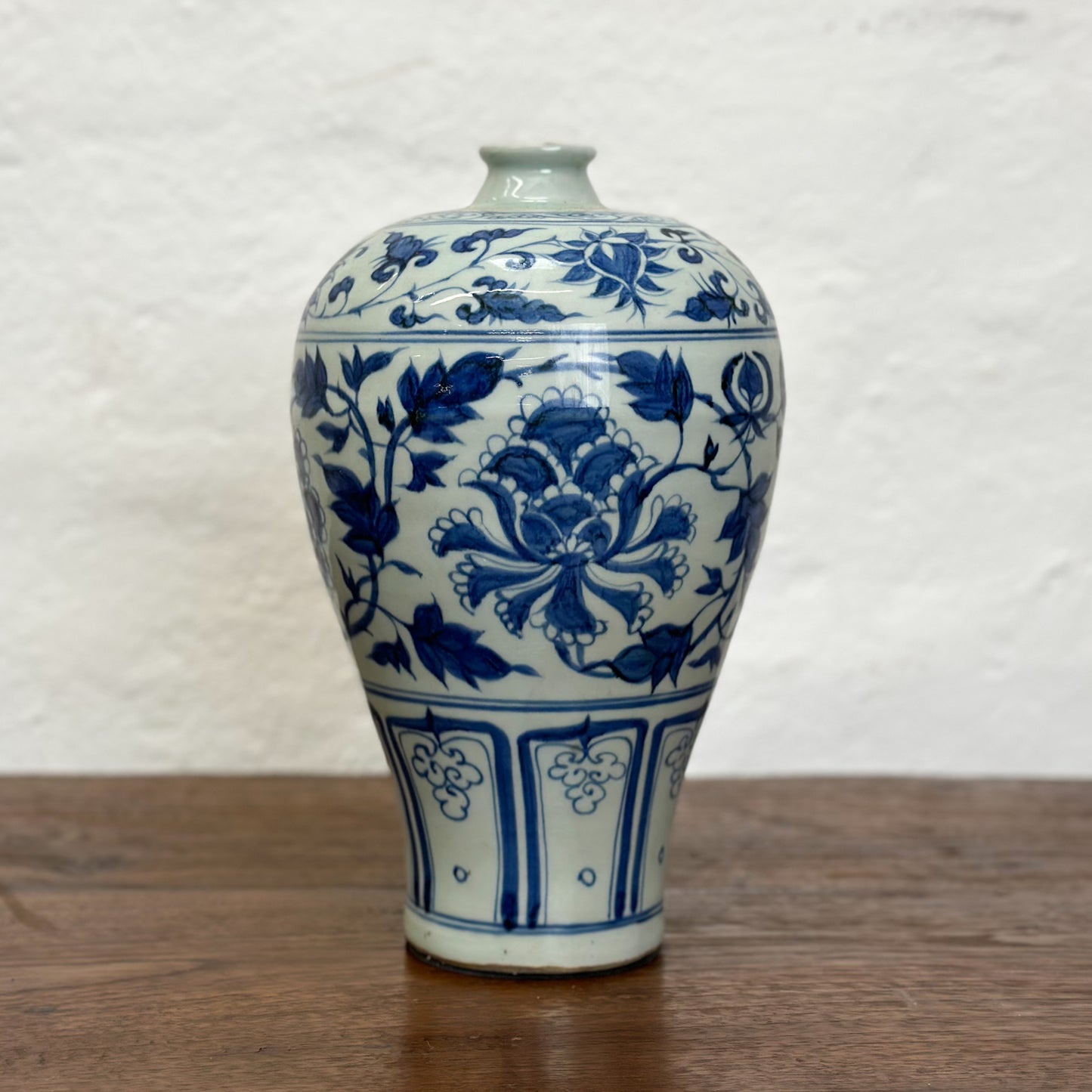 A blue and white ceramic vase with floral patterns, displayed against a neutral background.