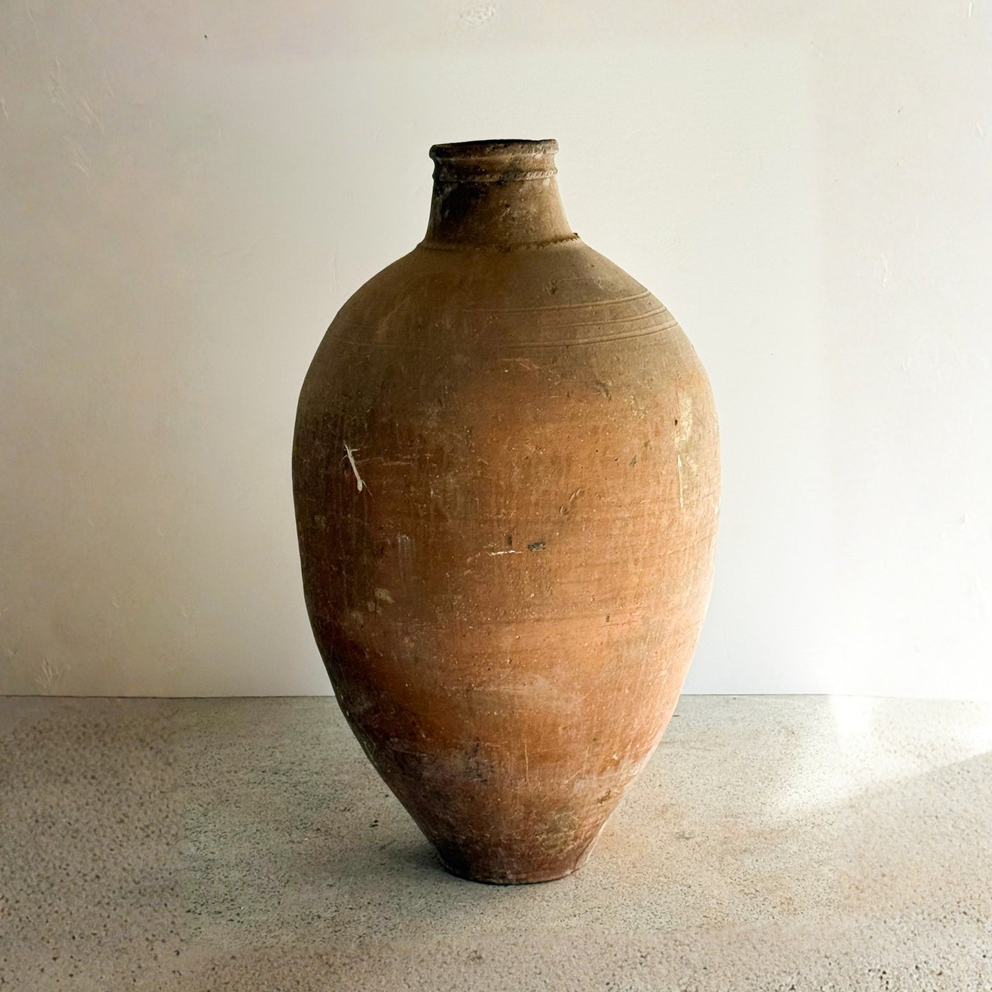 Large brown ceramic vase on a plain surface with a neutral background