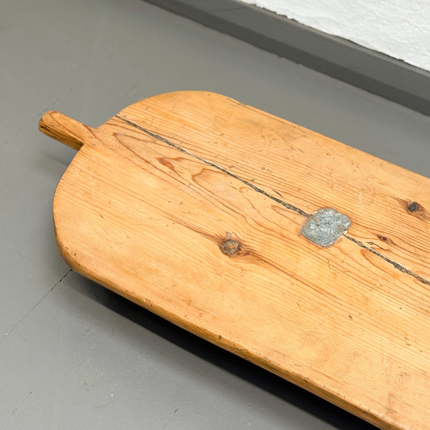 Wooden paddle with a metal weight on a gray surface