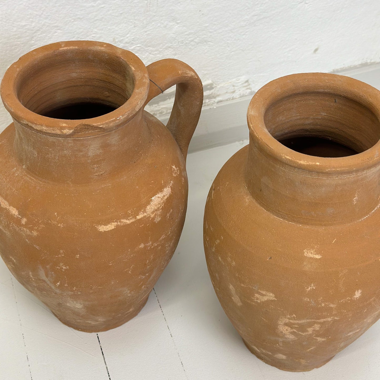 Two brown ceramic Turkish pots with a single handle on a white background.