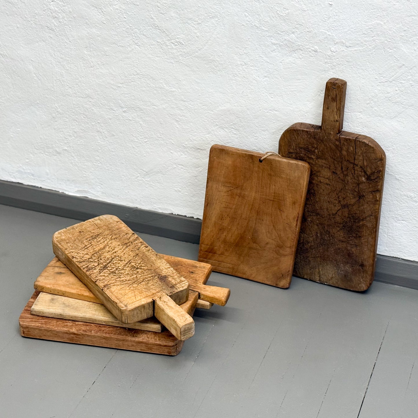 Set of wooden cutting boards of various sizes against a white wall.