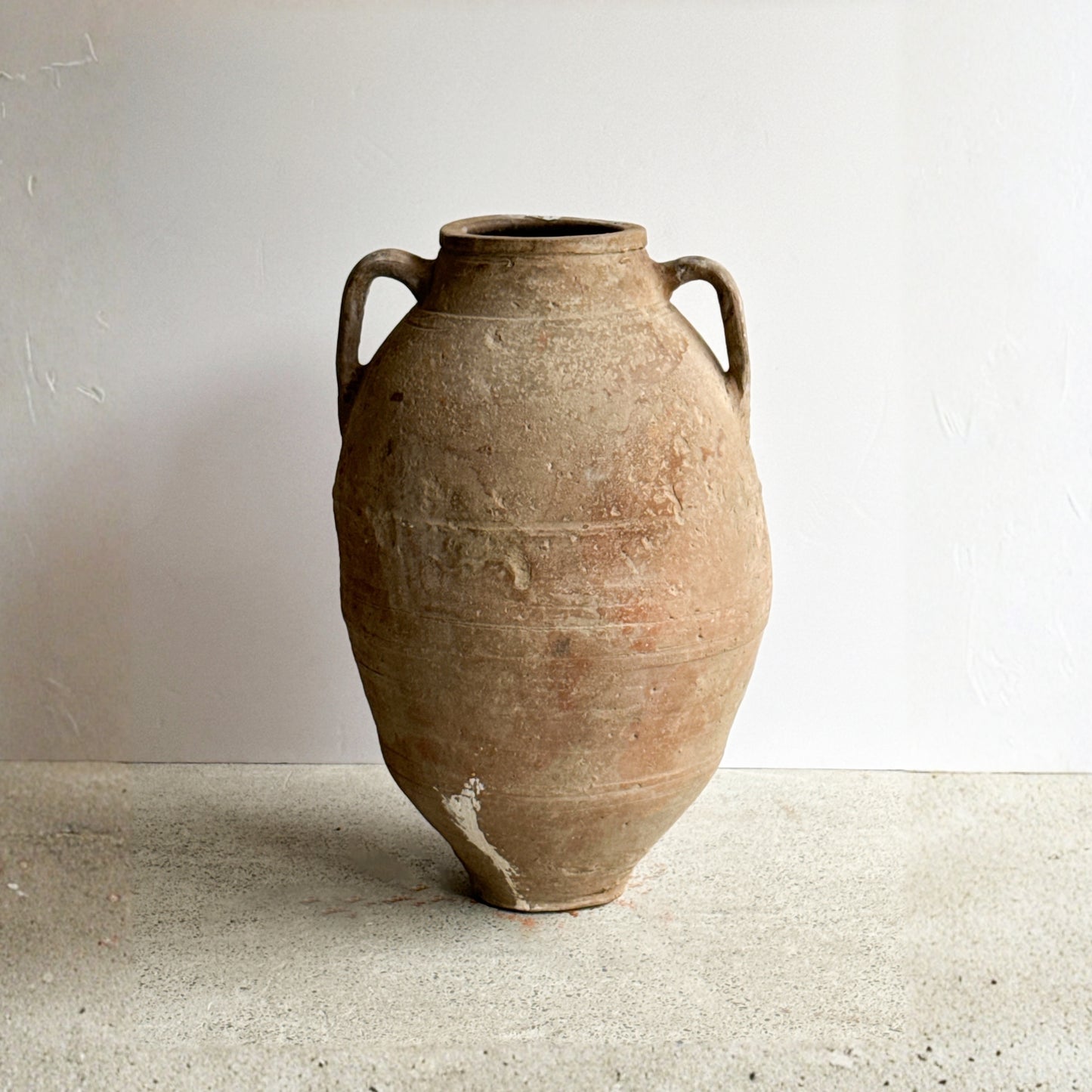 Vintage terracotta vase with handles on a neutral background