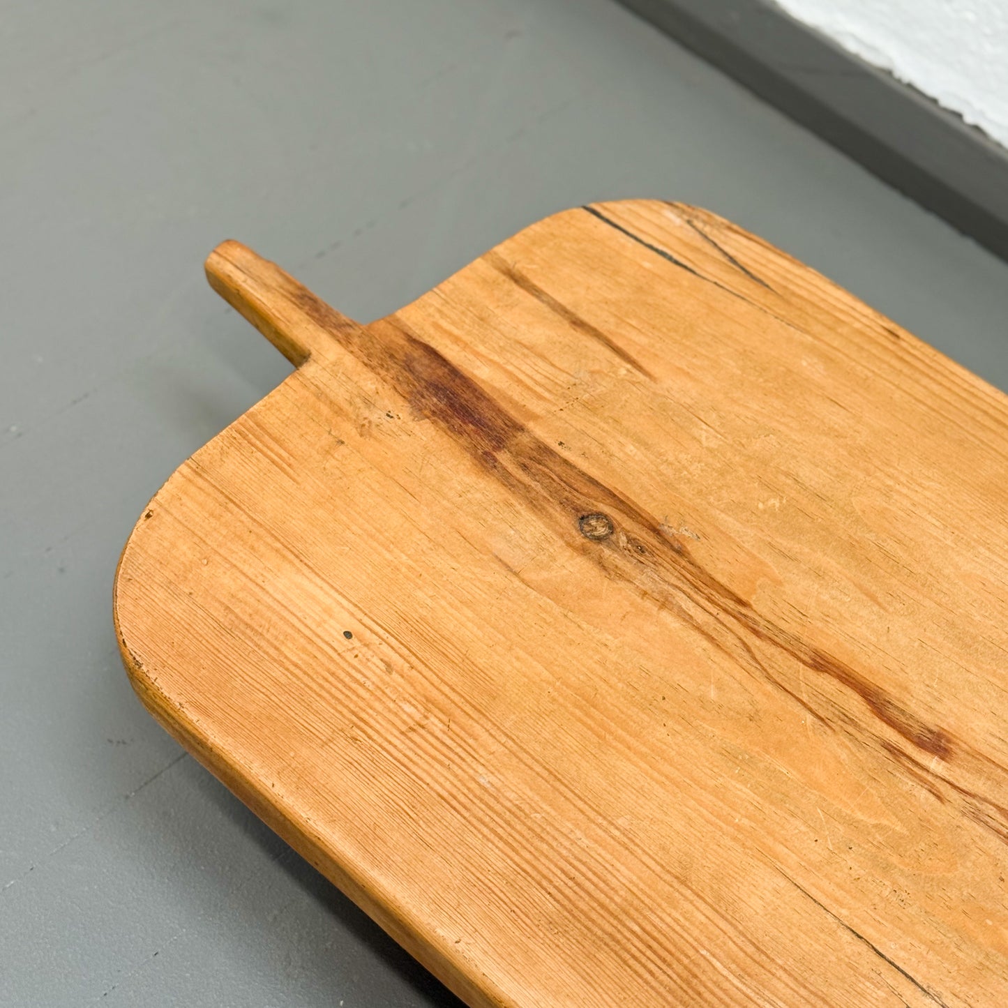 Wooden cutting board with a handle on a gray surface