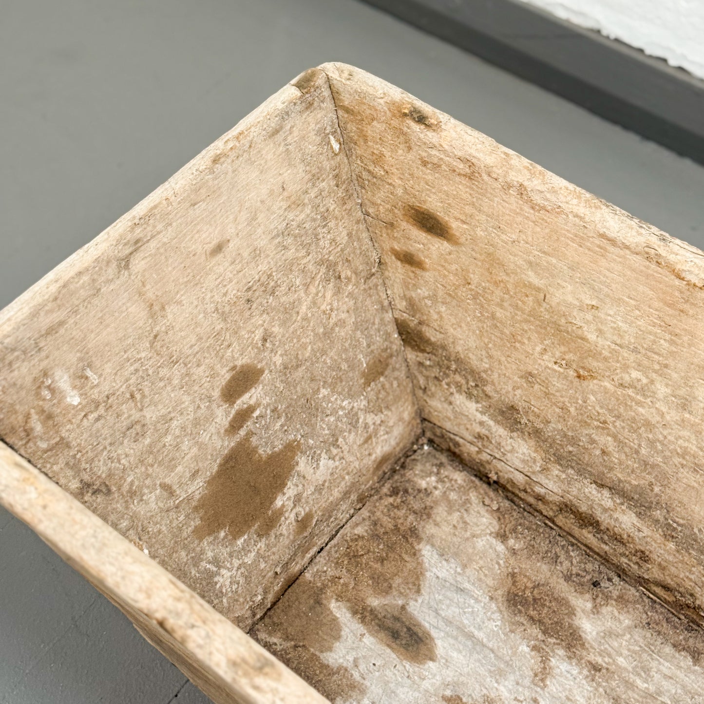Close-up of a wooden surface with visible grain and brown spots on a gray background