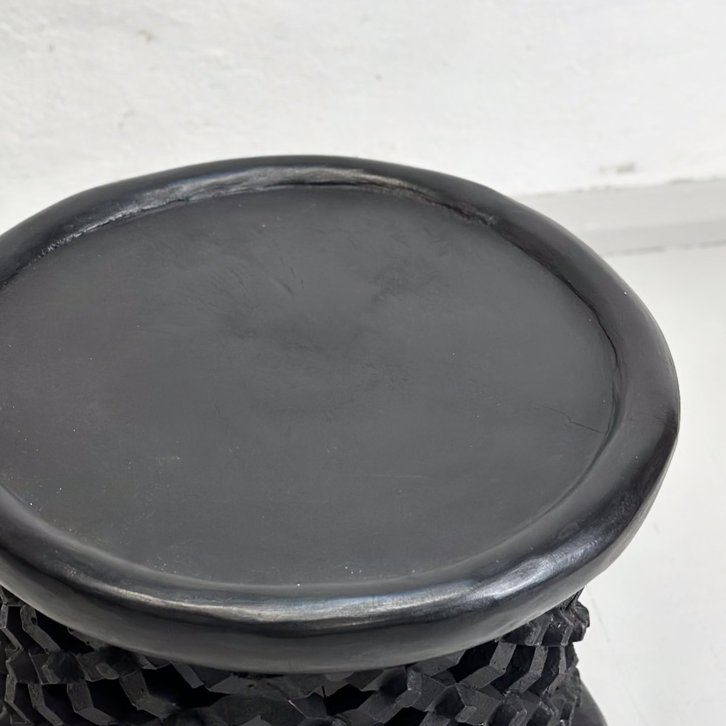 A small Bamileke stool from Cameroon with a geometric pattern, predominantly in black color.
