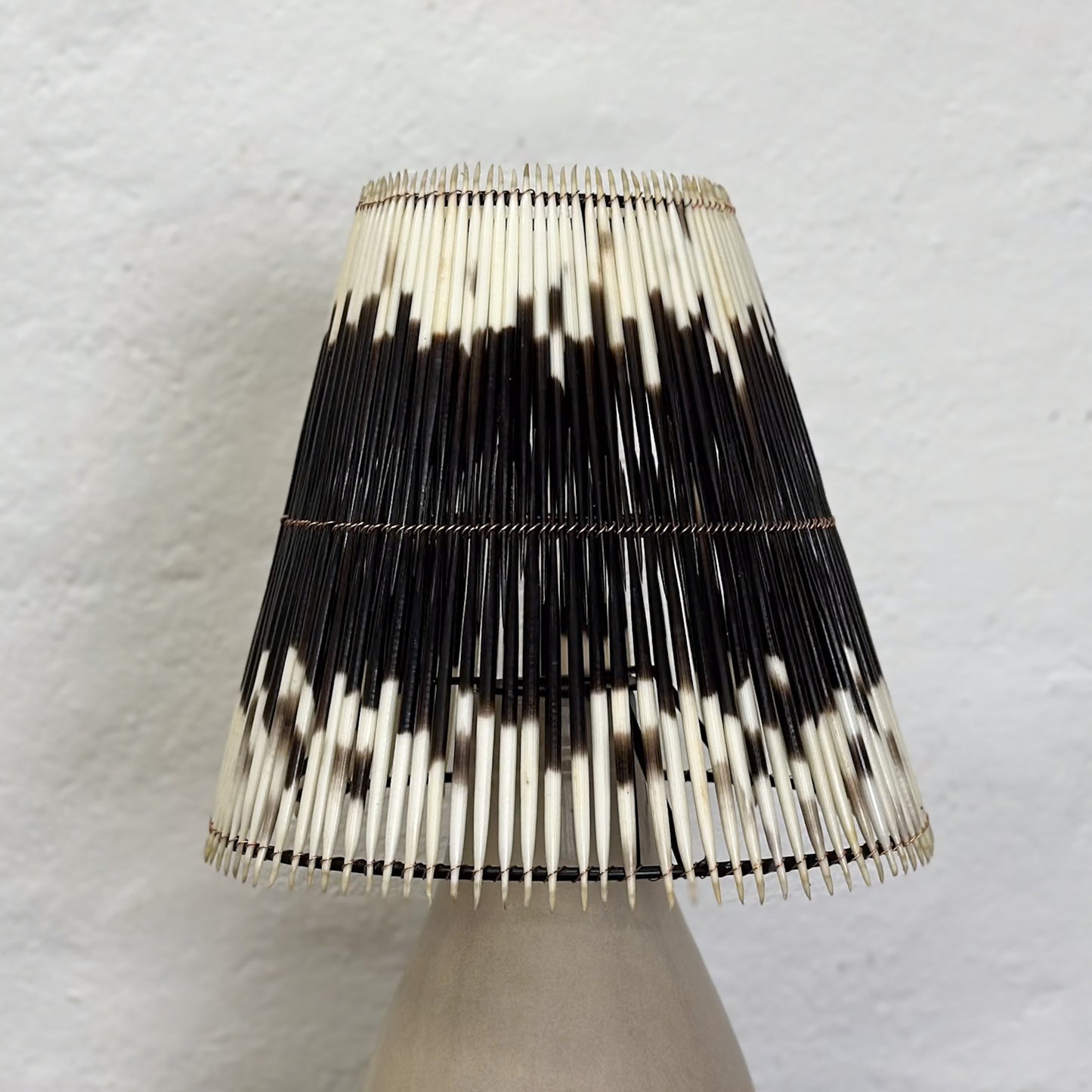 A lampshade with a geometric pattern of black and white quills.