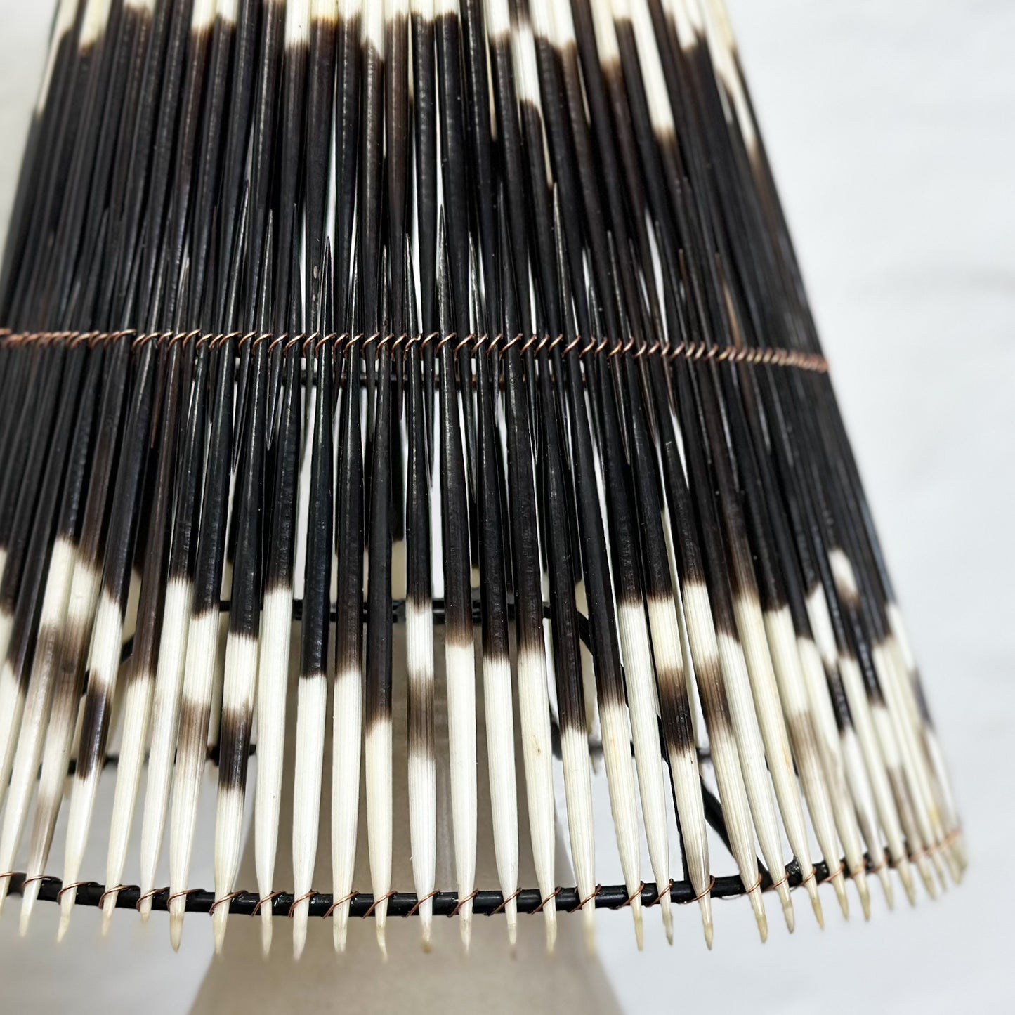 A lampshade with a geometric pattern of black and white quills.