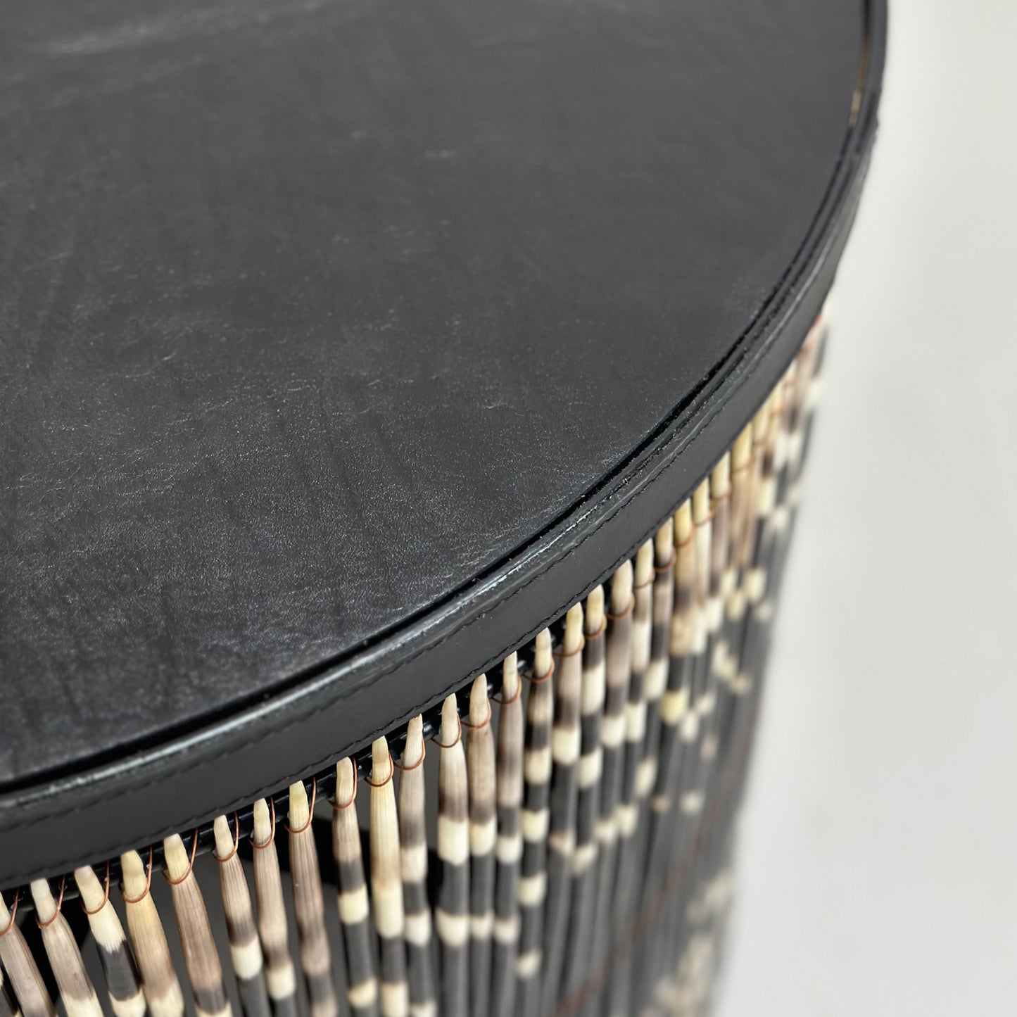 A round porcupine quill table with black and white quills, placed on a neutral background.