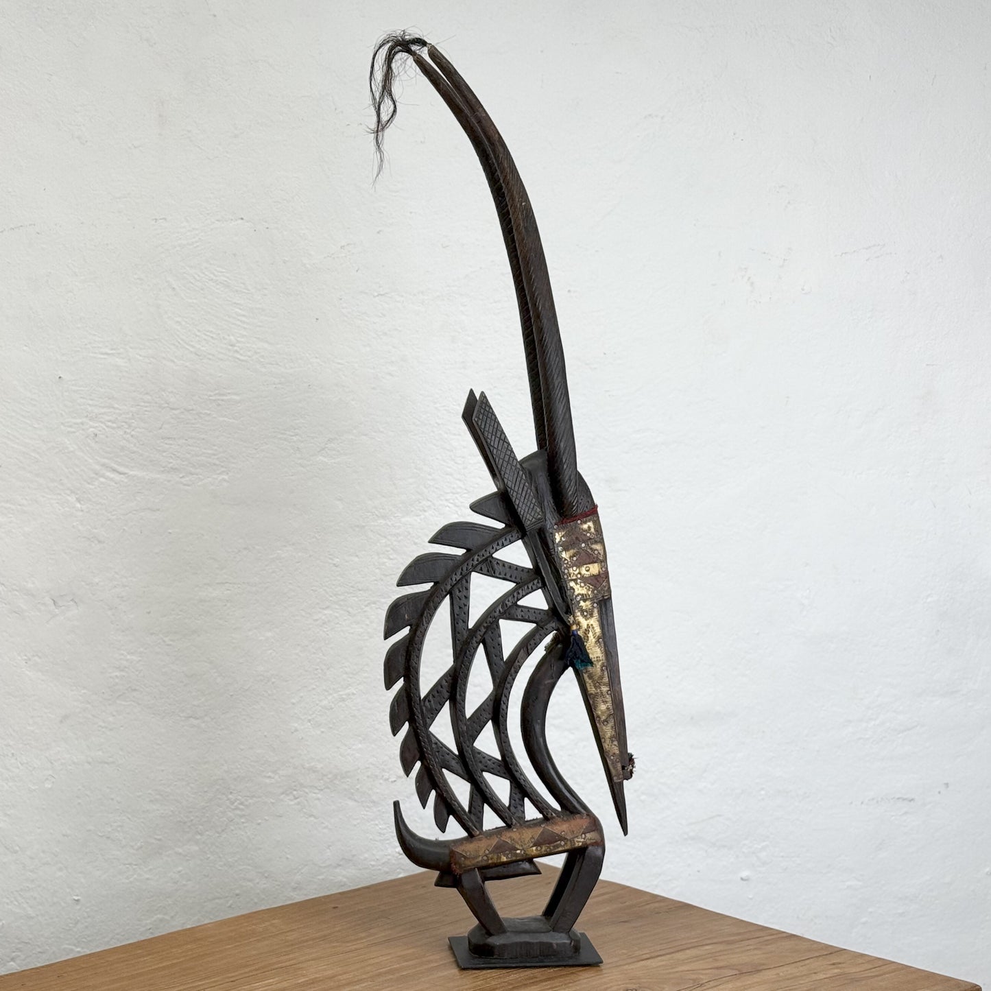 A sculpture of a mythical creature with a metal structure having a mix of dark and light brown colors, standing upright against a plain background.