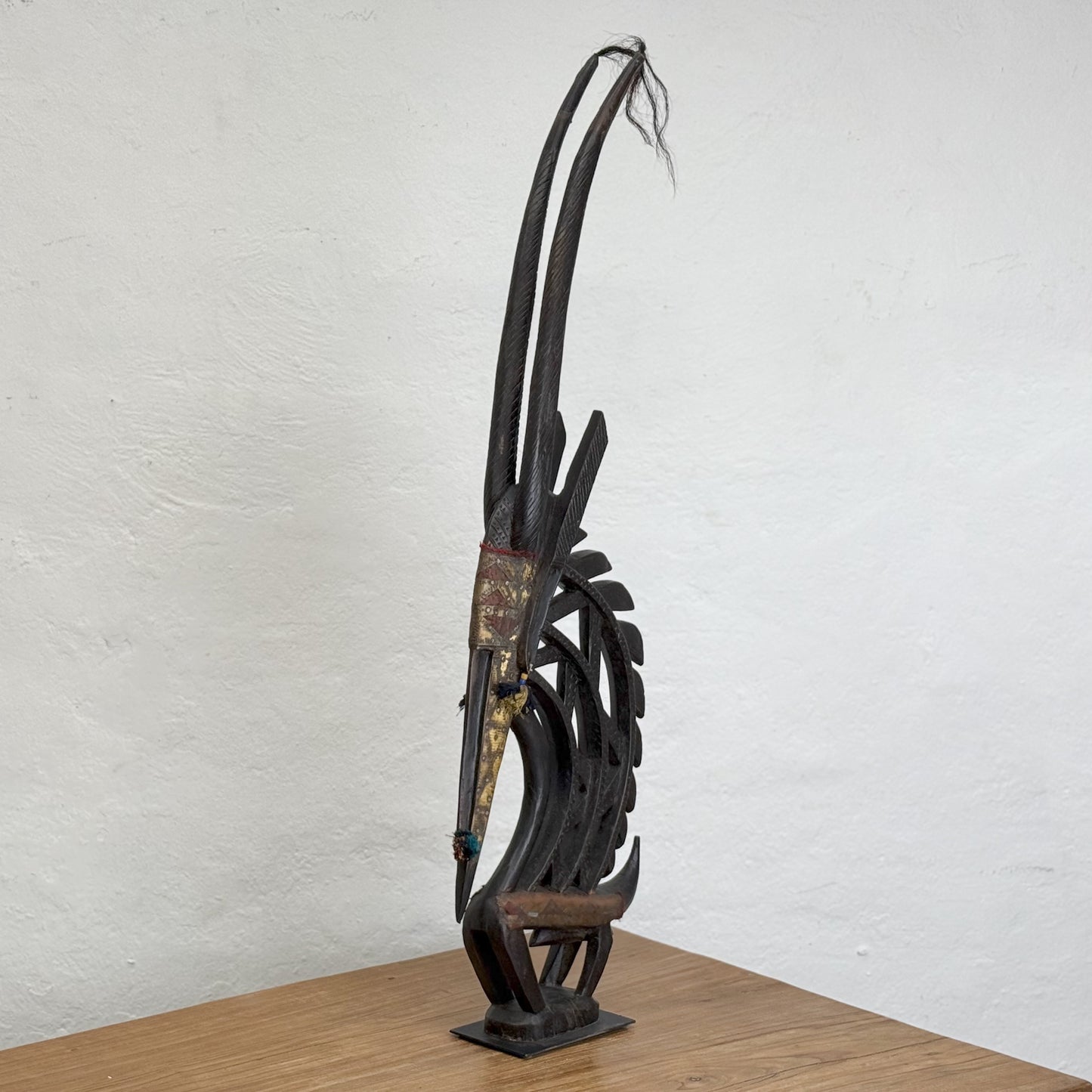 A sculpture of a mythical creature with a metal structure having a mix of dark and light brown colors, standing upright against a plain background.