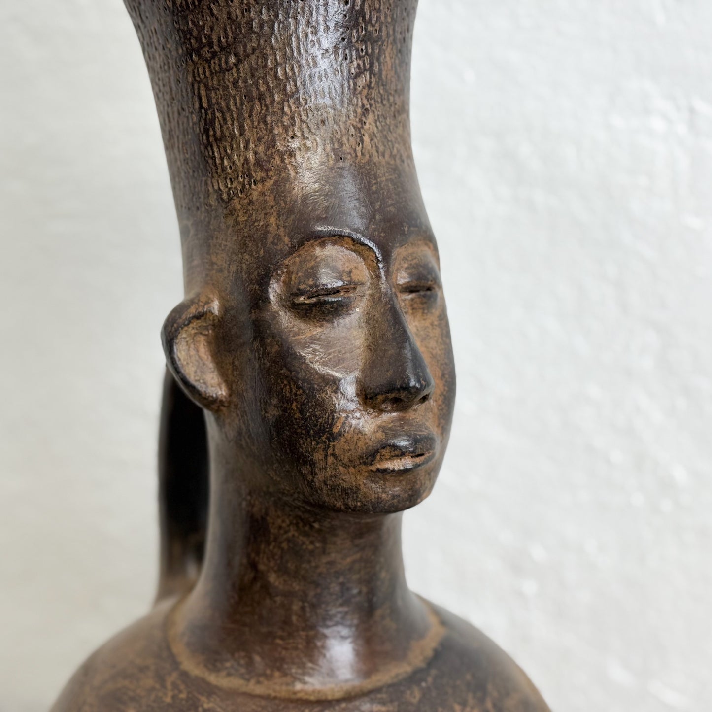 Close-up of a bronze sculpture of a human head on a plain background