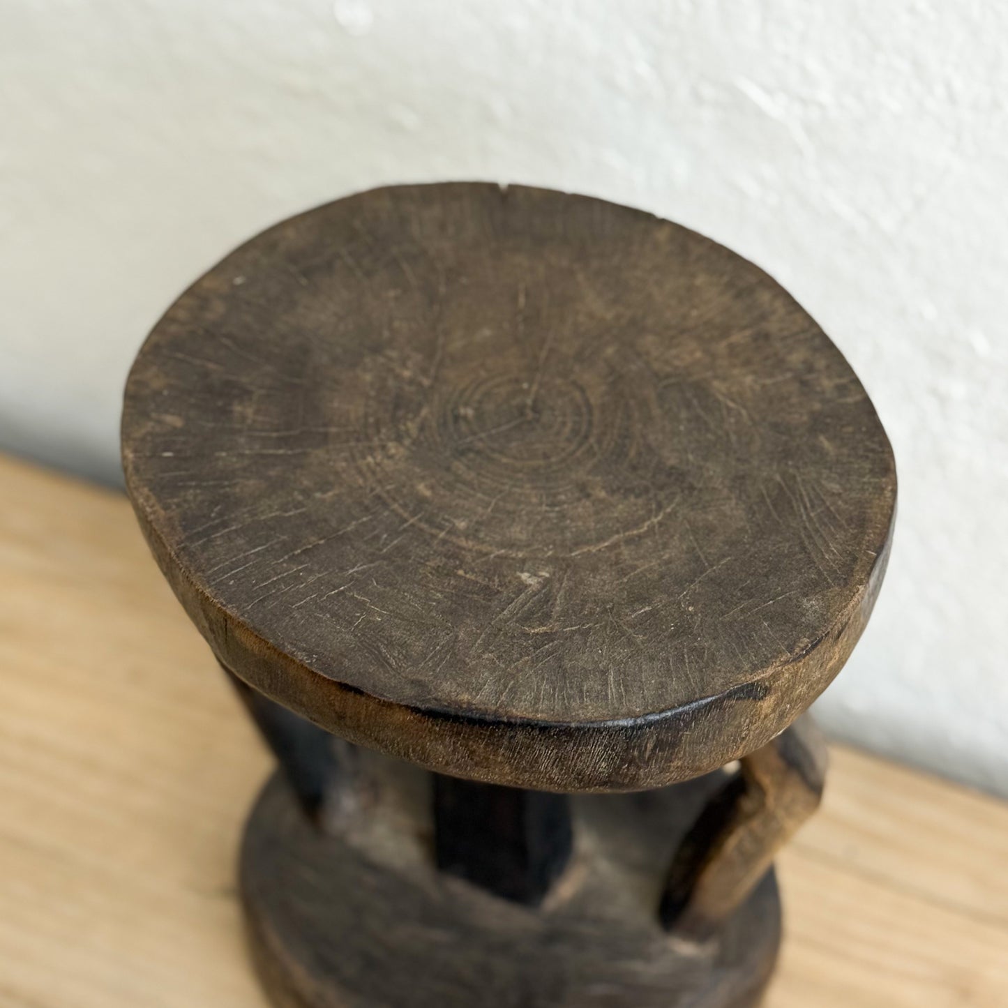 Wooden stool with a round top and spiral design on a white background