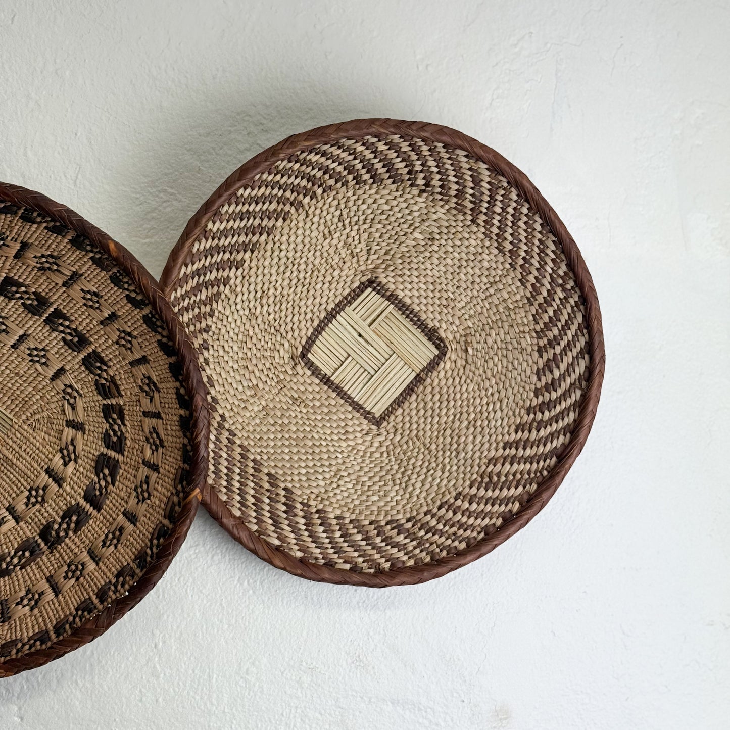 Two woven baskets with different patterns on a white background