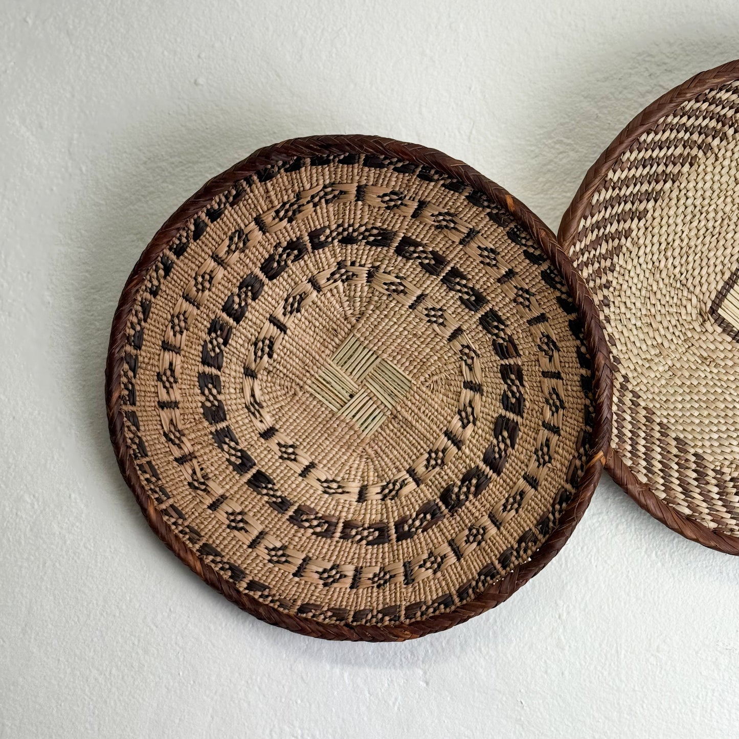 Two woven coasters with intricate patterns on a light background
