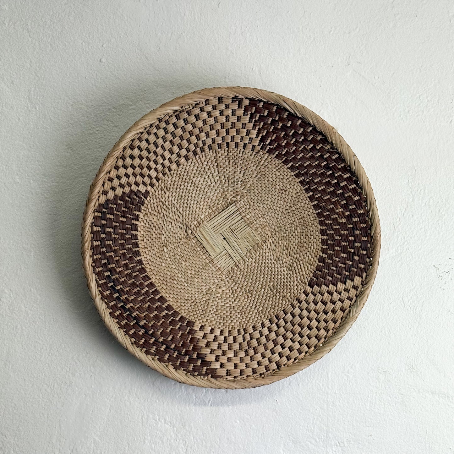 Woven basket with a geometric pattern on a light gray background