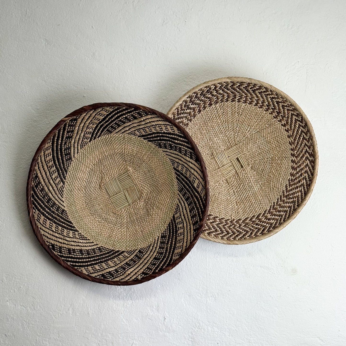 Two woven baskets with geometric patterns on a white background