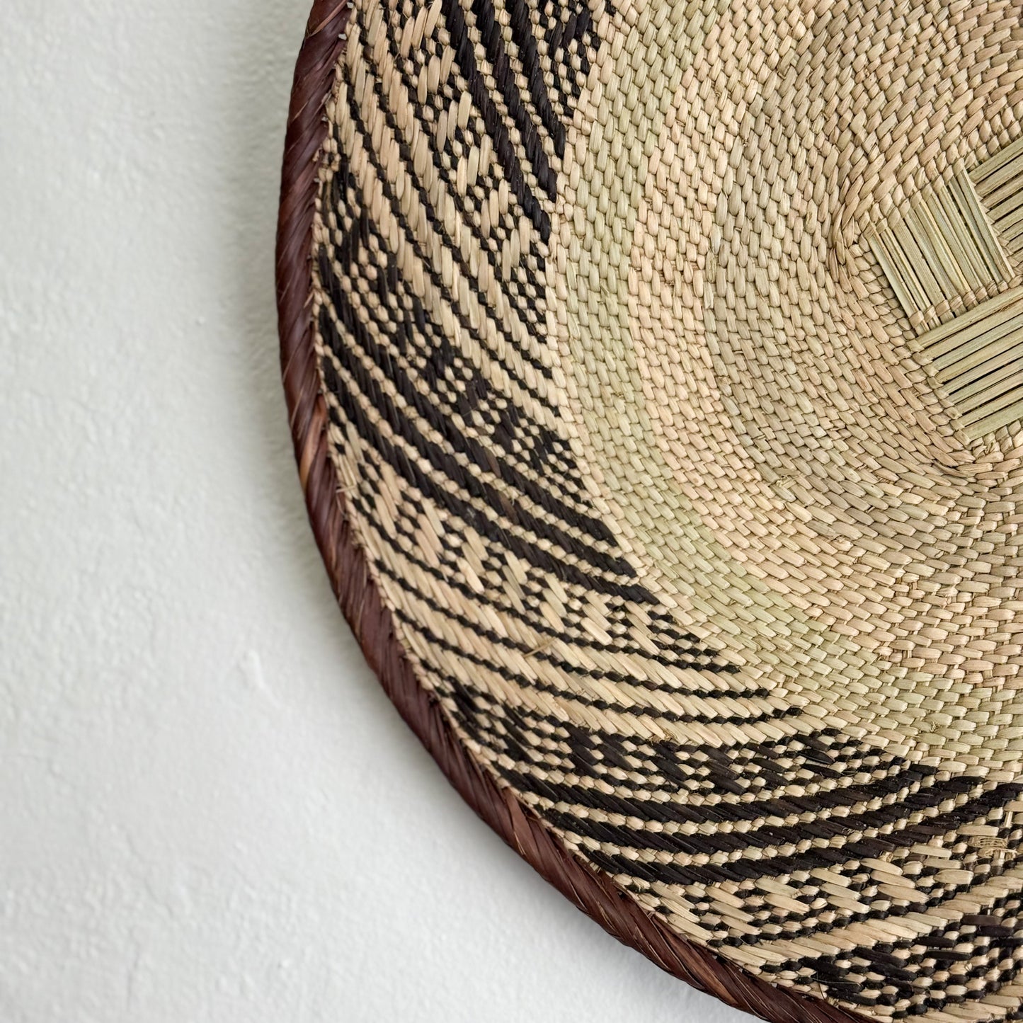 Close-up of a woven basket with a geometric pattern on a white background