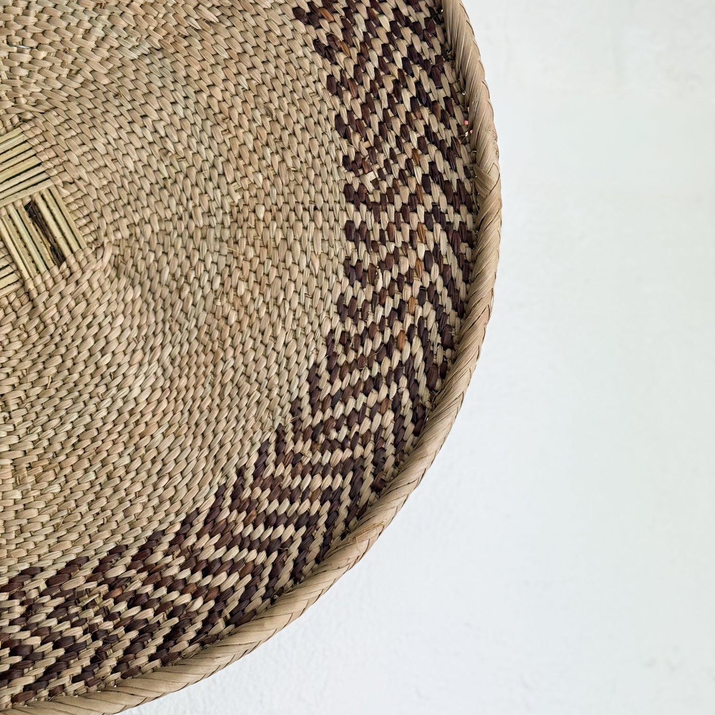 Close-up of a woven basket with a geometric pattern on a white background