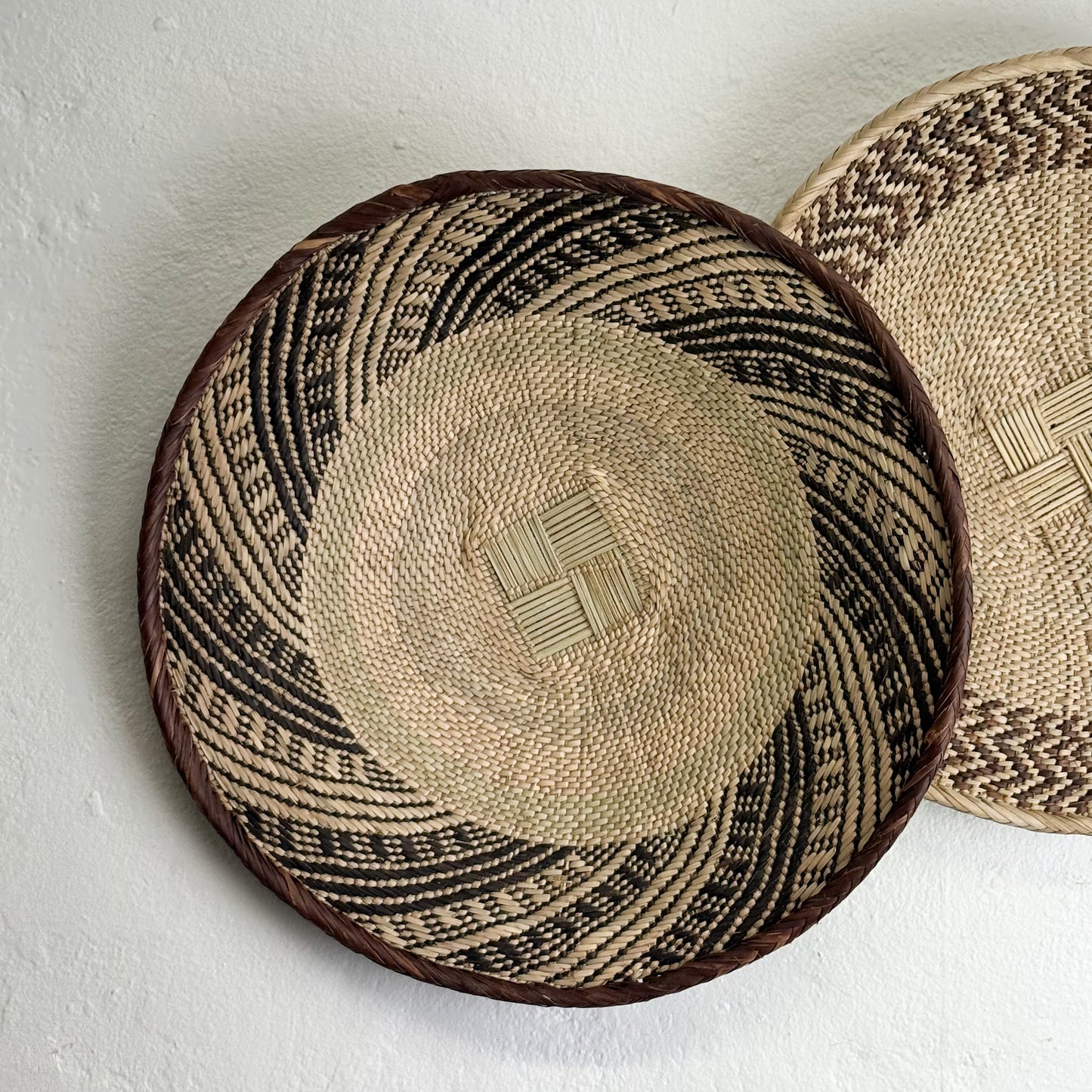 Two woven baskets with geometric patterns on a light background