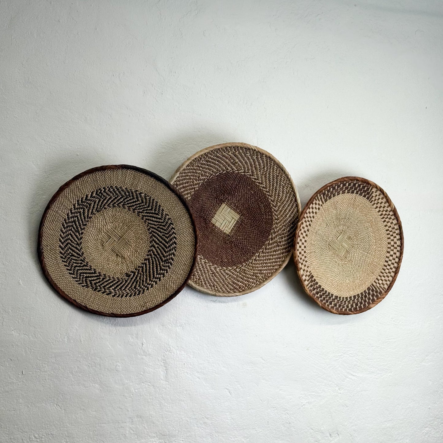Three woven baskets of different patterns on a light gray background
