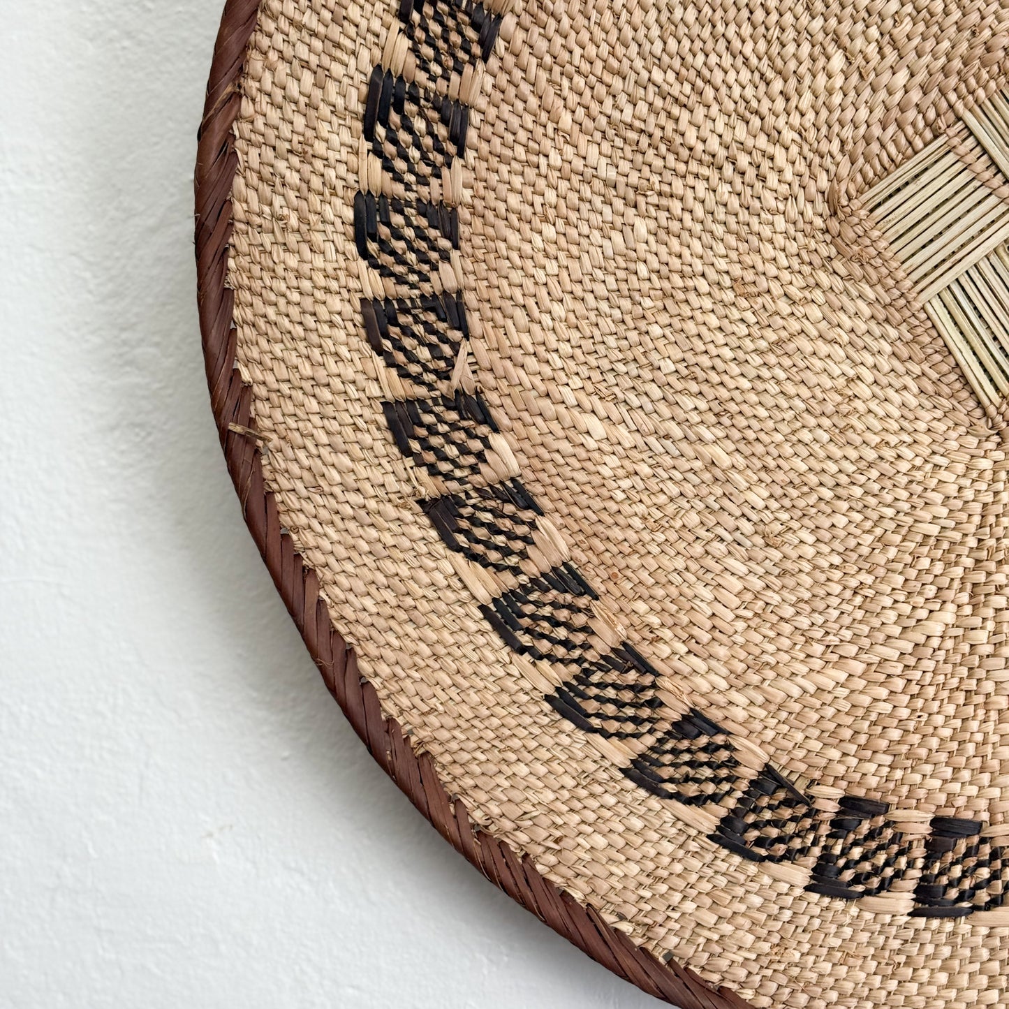 Close-up of a woven basket with decorative patterns on a white background