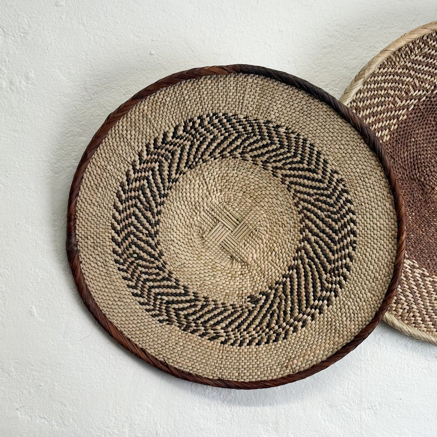Round woven placemats with a herringbone pattern on a light background