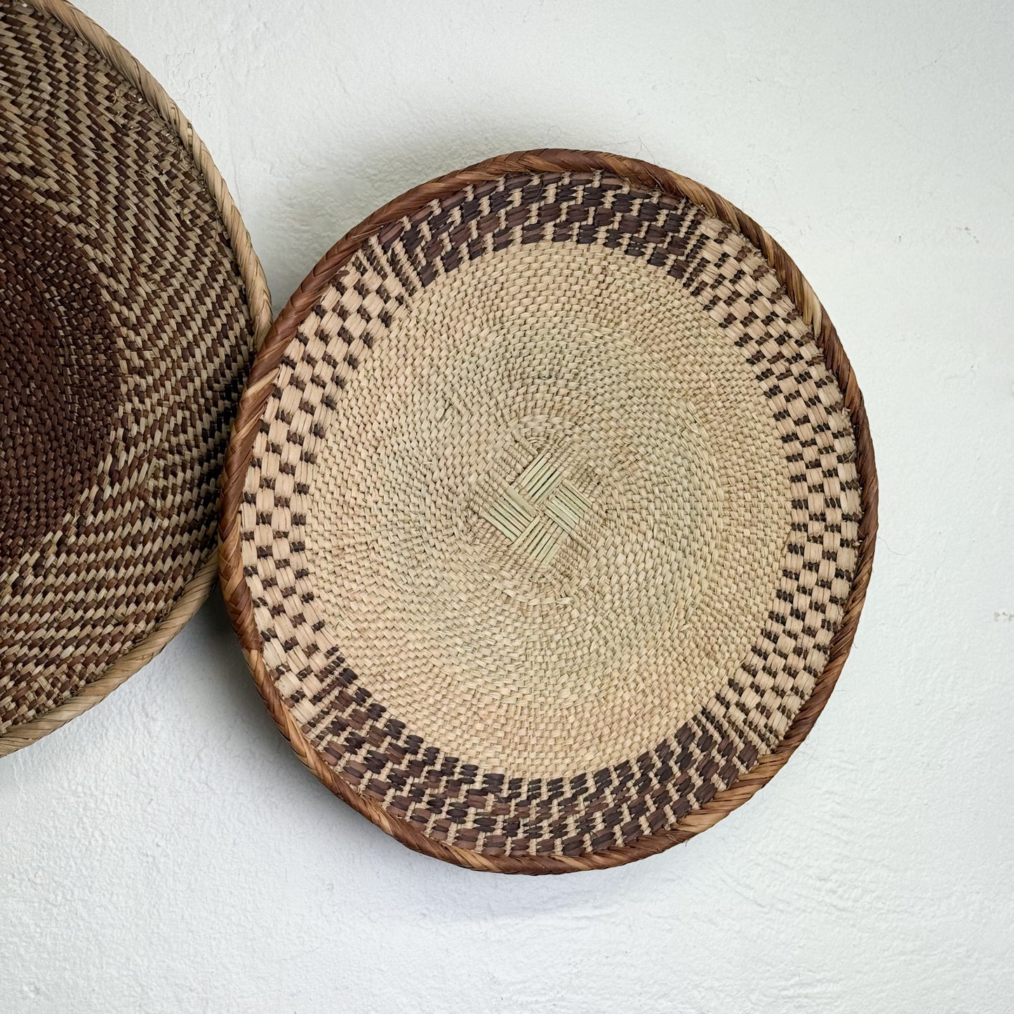 Two woven baskets with a geometric pattern on a white background