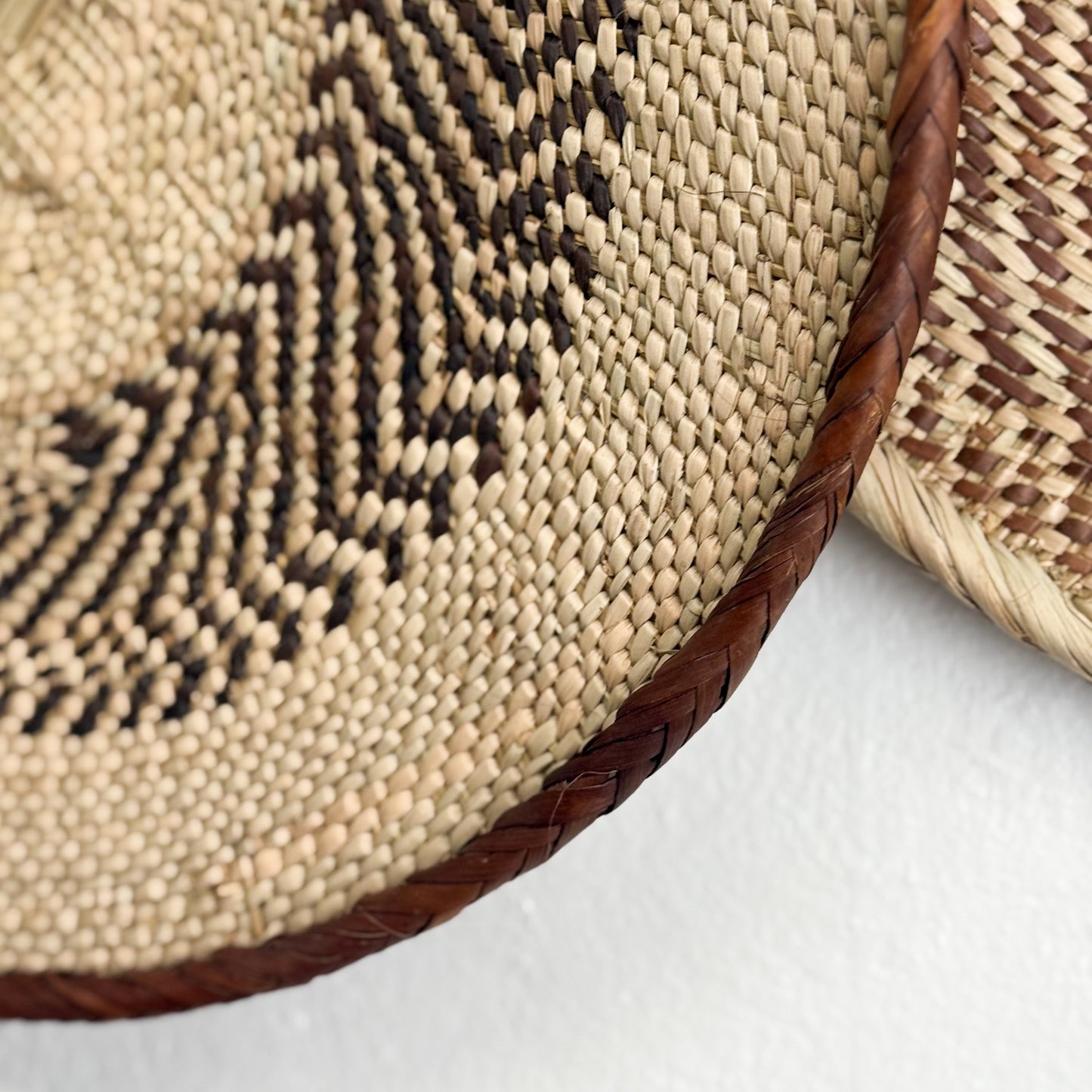 Close-up of a woven basket with a braided edge on a white background