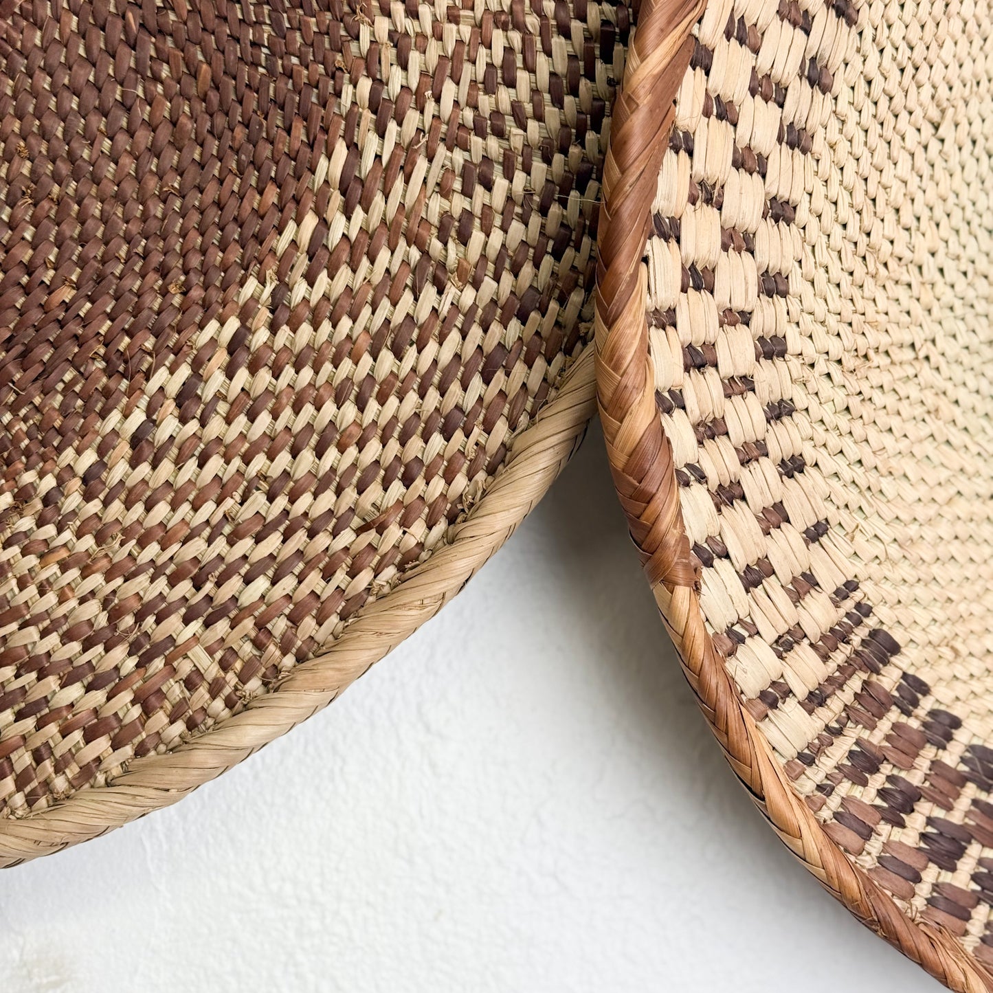 Close-up of two woven rattan mats with a textured pattern on a white background